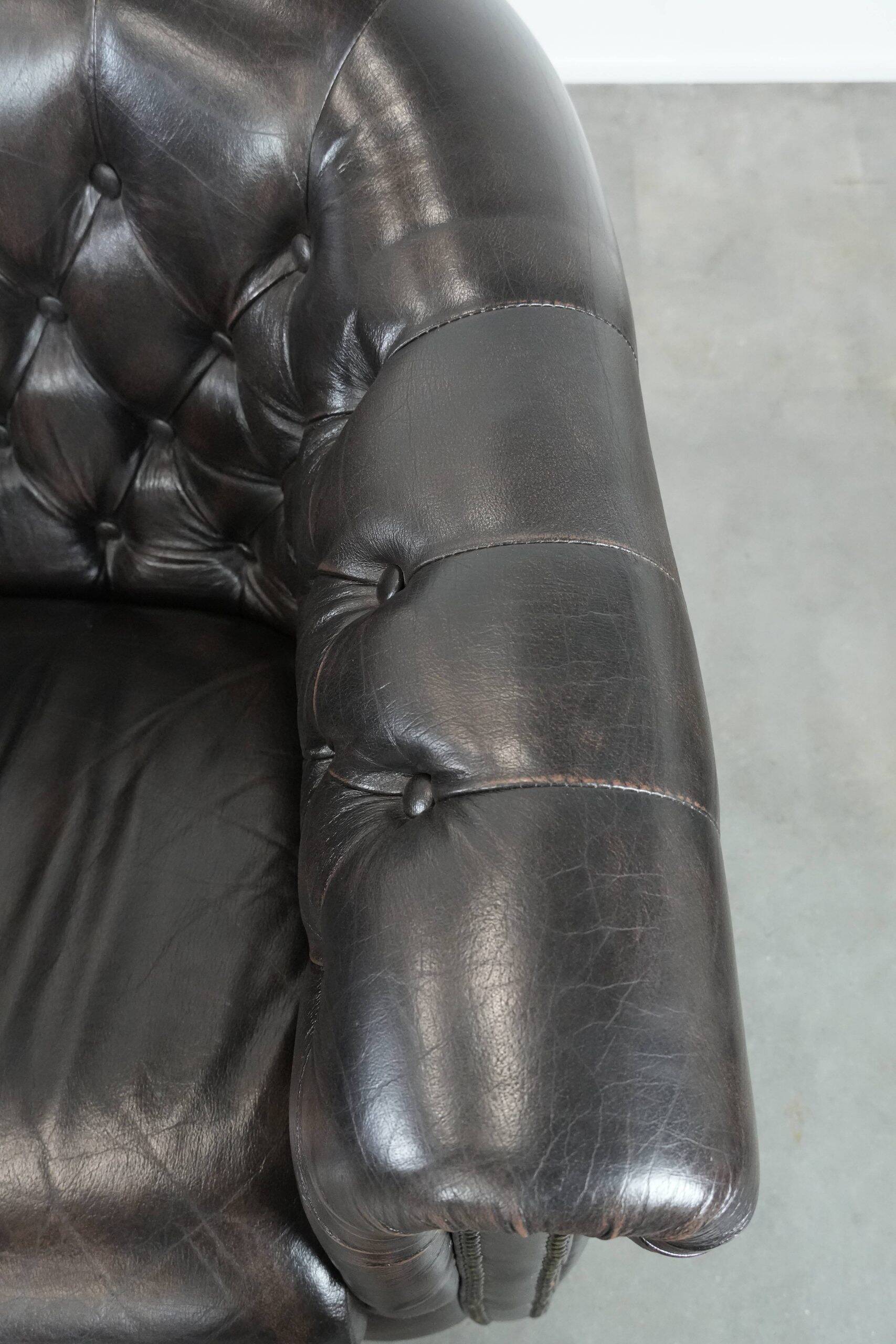 Ensemble de deux luxueux fauteuils club Chesterfield en cuir de vachette noir.
