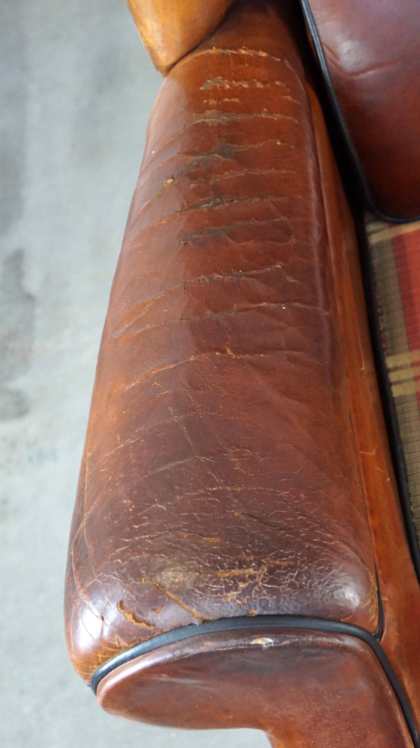 Very large worn sheepskin wing chair with a checked seat cushion