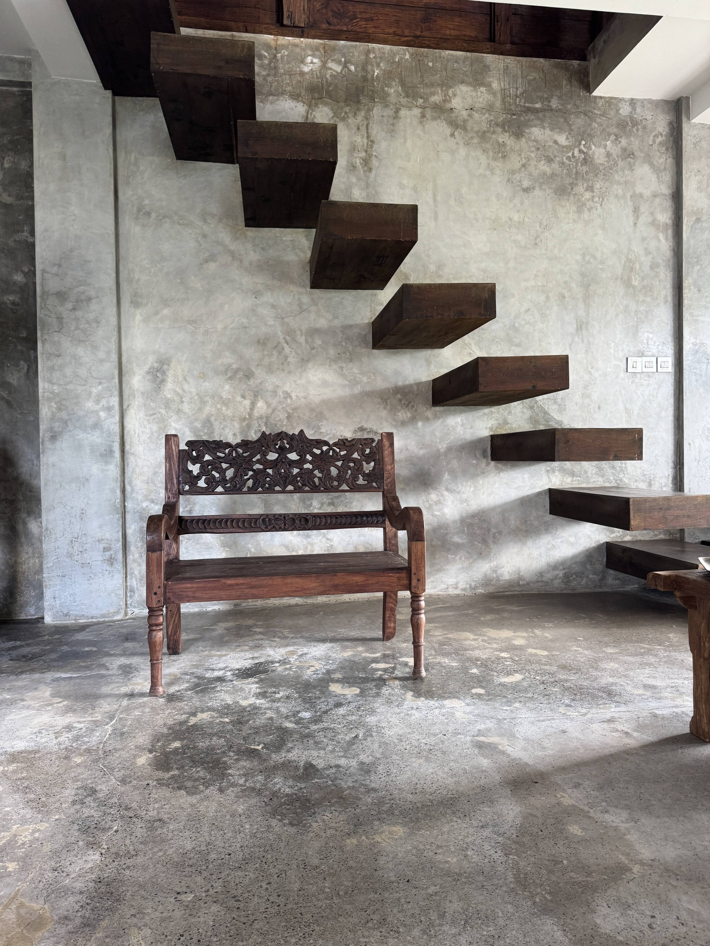 Small antique Indonesian bench in carved teak with plant and floral motifs.