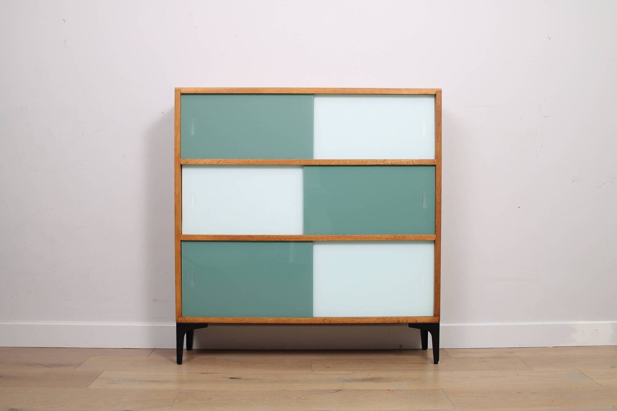 A vintage mid-century 3 tiered bookcase with glass sliding doors