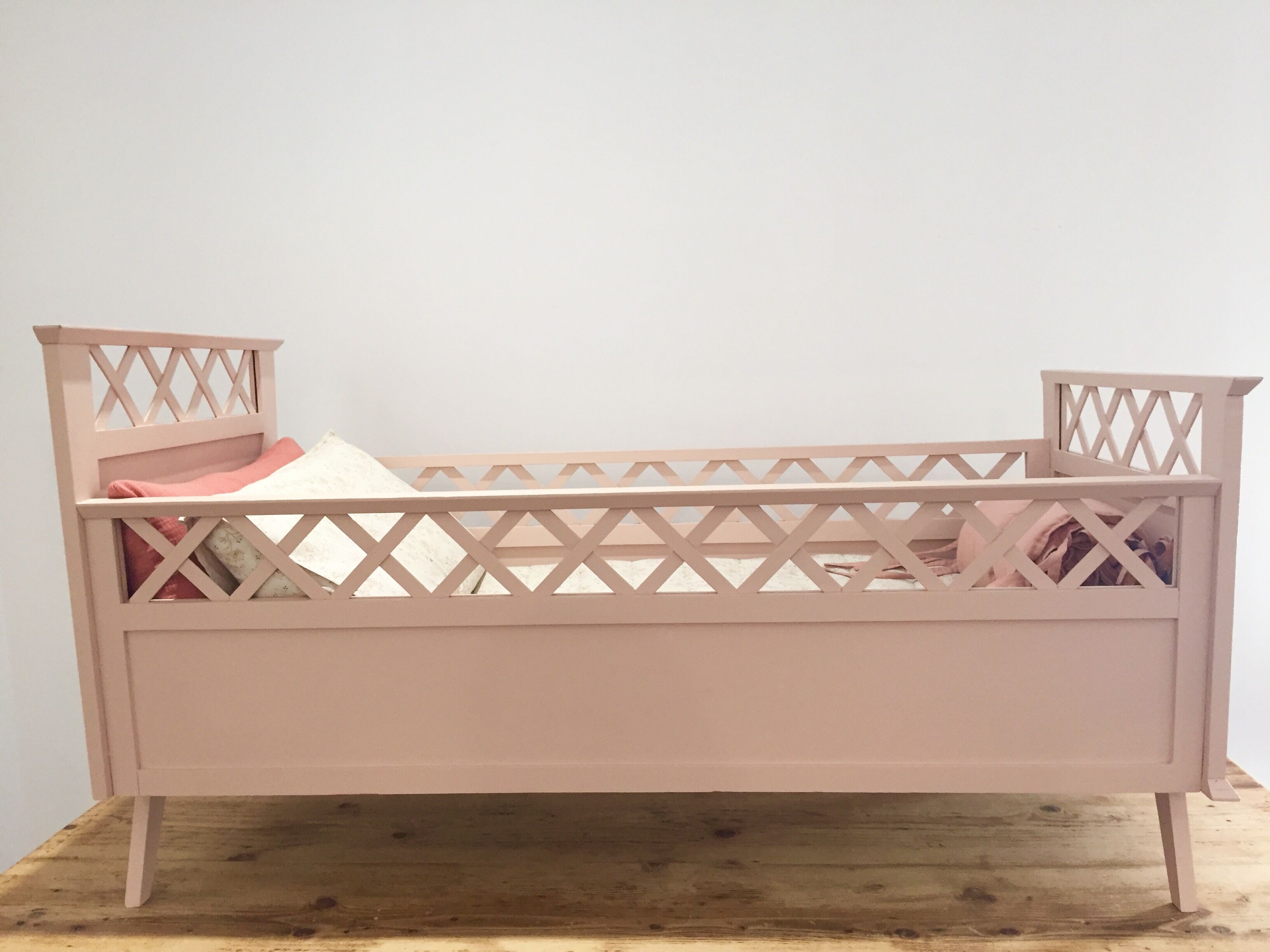 Vintage wooden baby bed in old pink