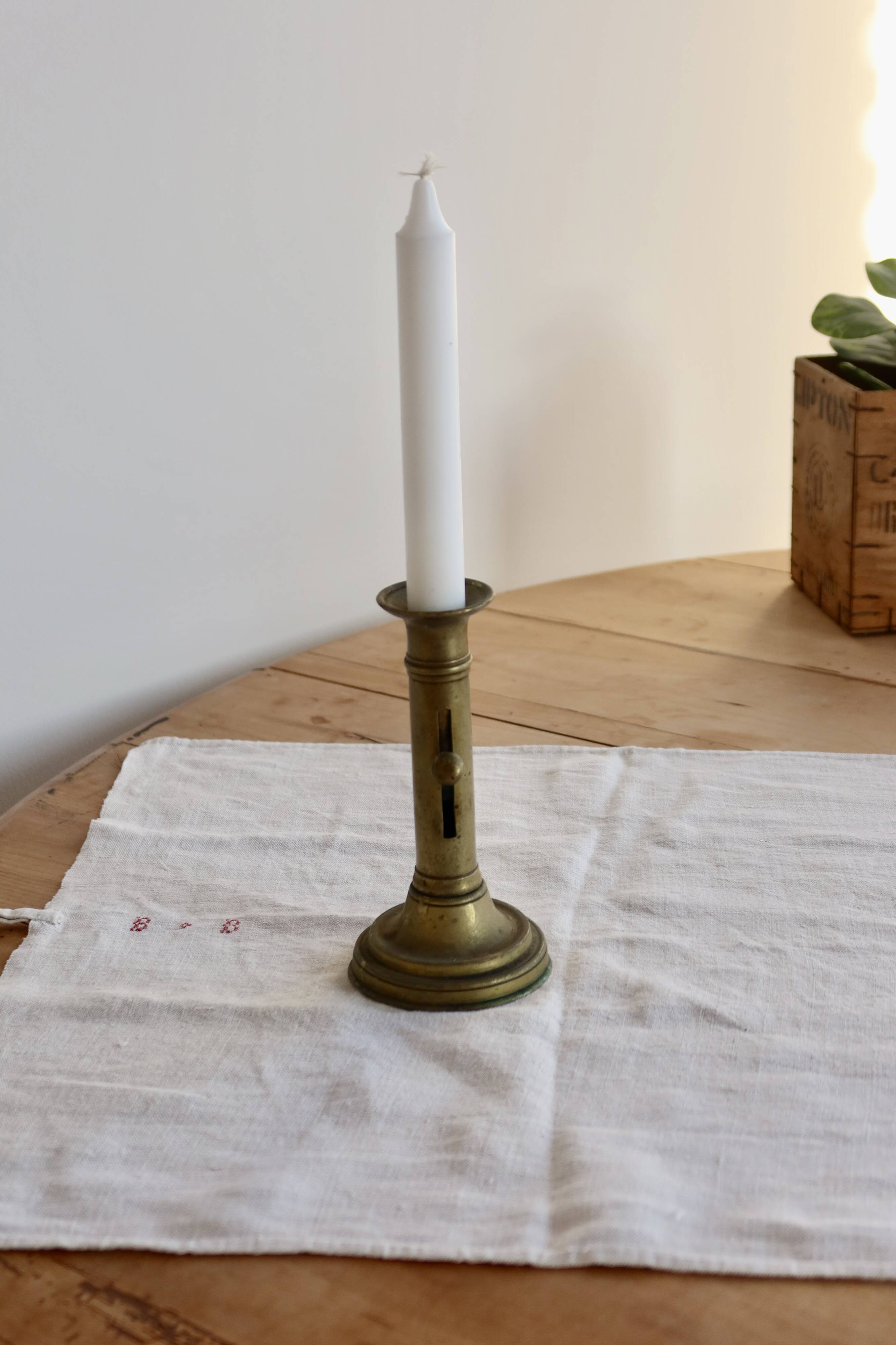 Antique brass candlestick with a push button.