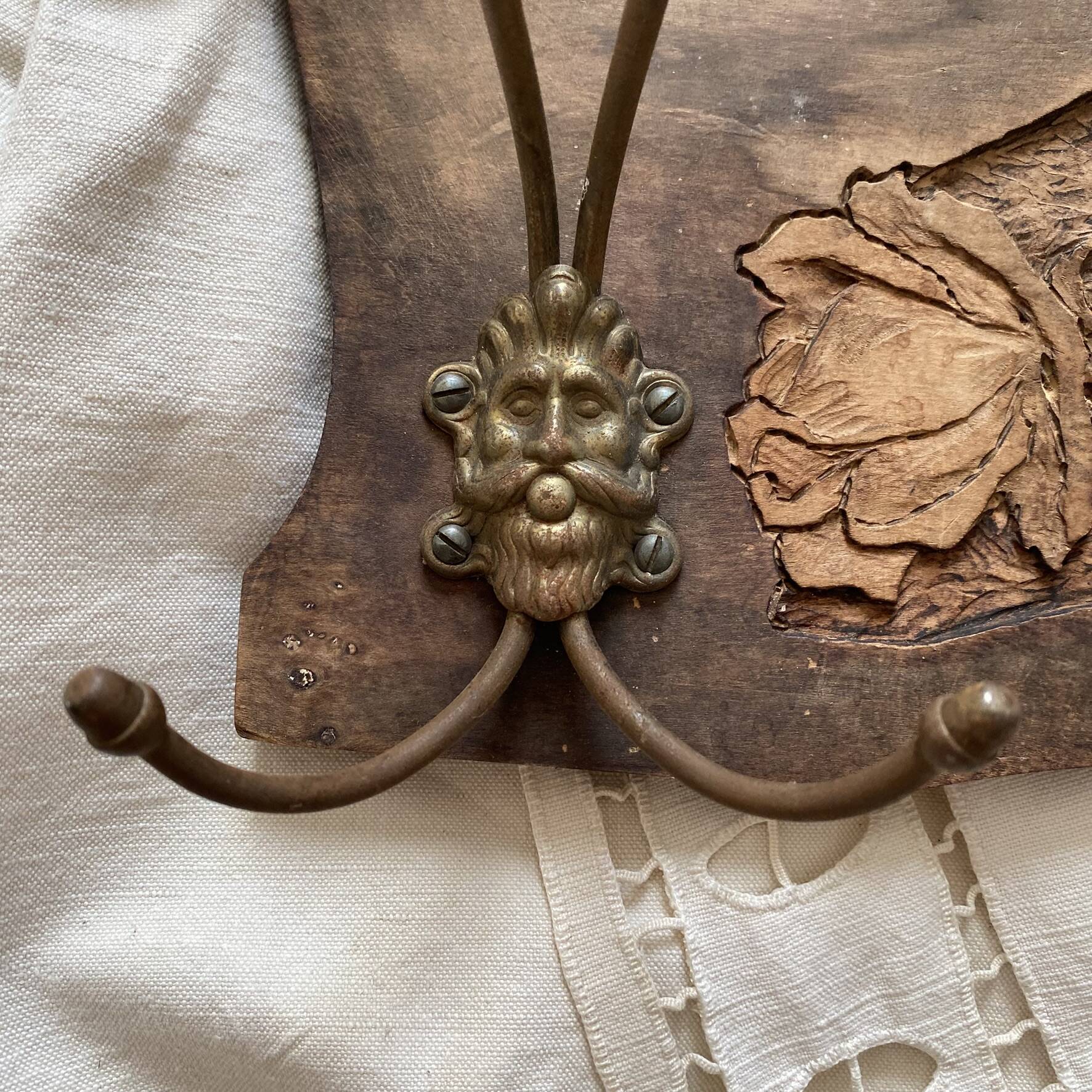 Wall-mounted coat rack in carved wood with rose decoration.