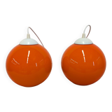 Pair of spherical pendant lights in orange opaline, France circa 1970.