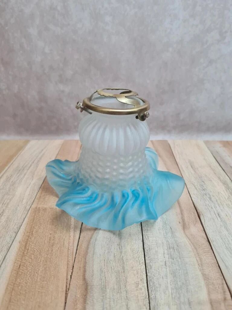 An antique lampshade in frosted glass with delicate blue edges.