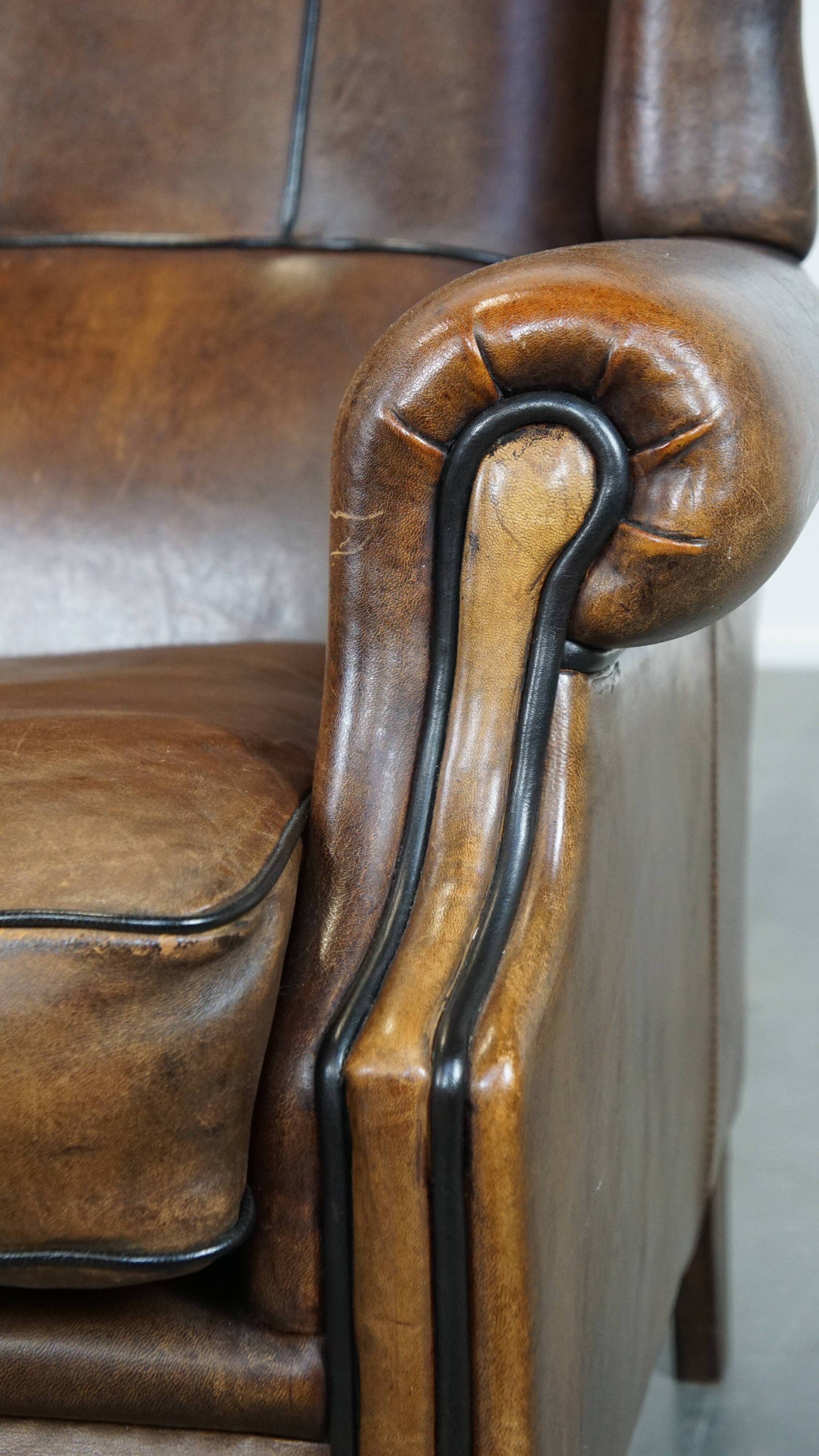 Vintage sheepskin wingback chair finished with black piping