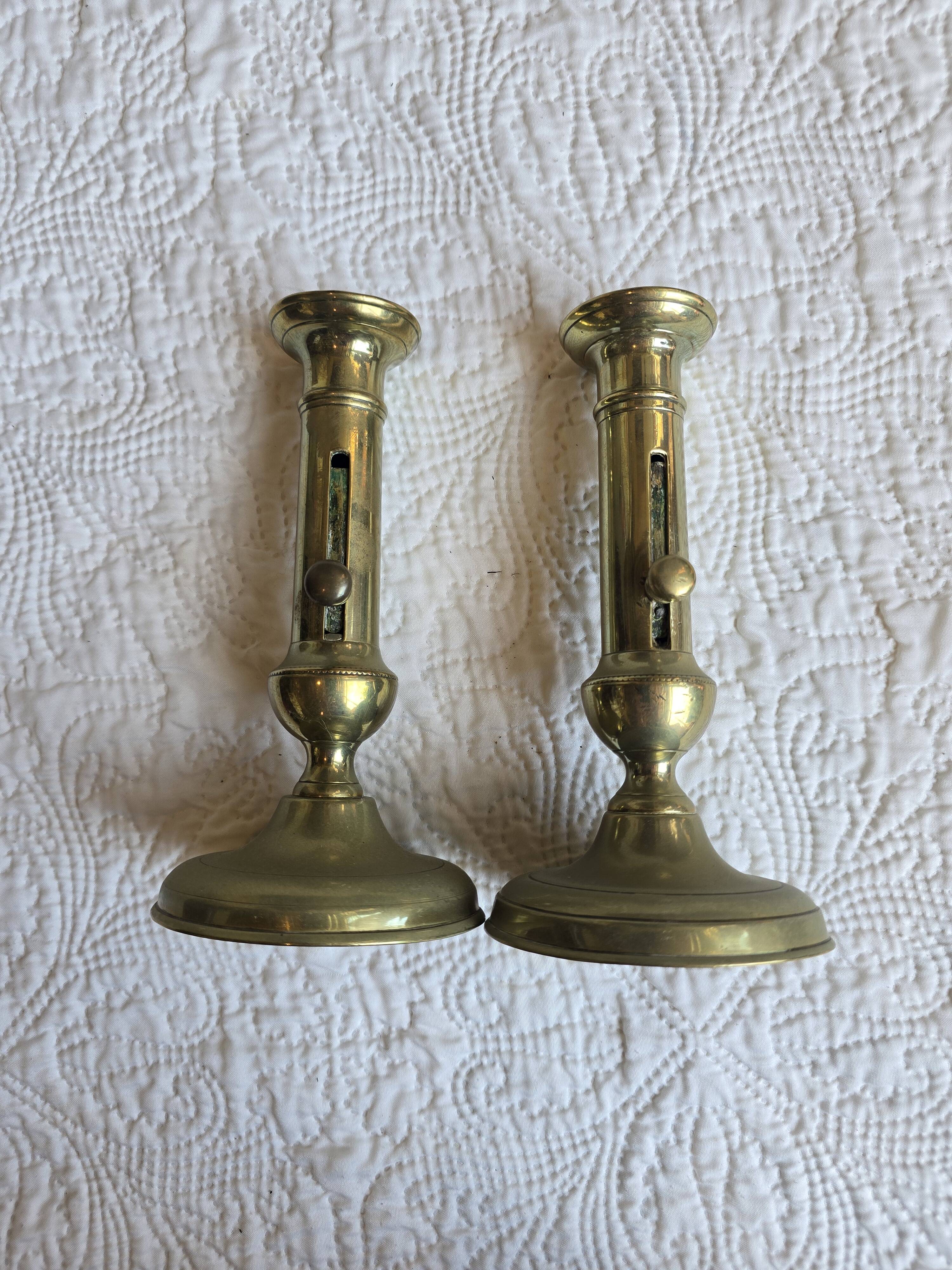 Pair of antique brass candlesticks with adjustable push mechanism from the 19th century.