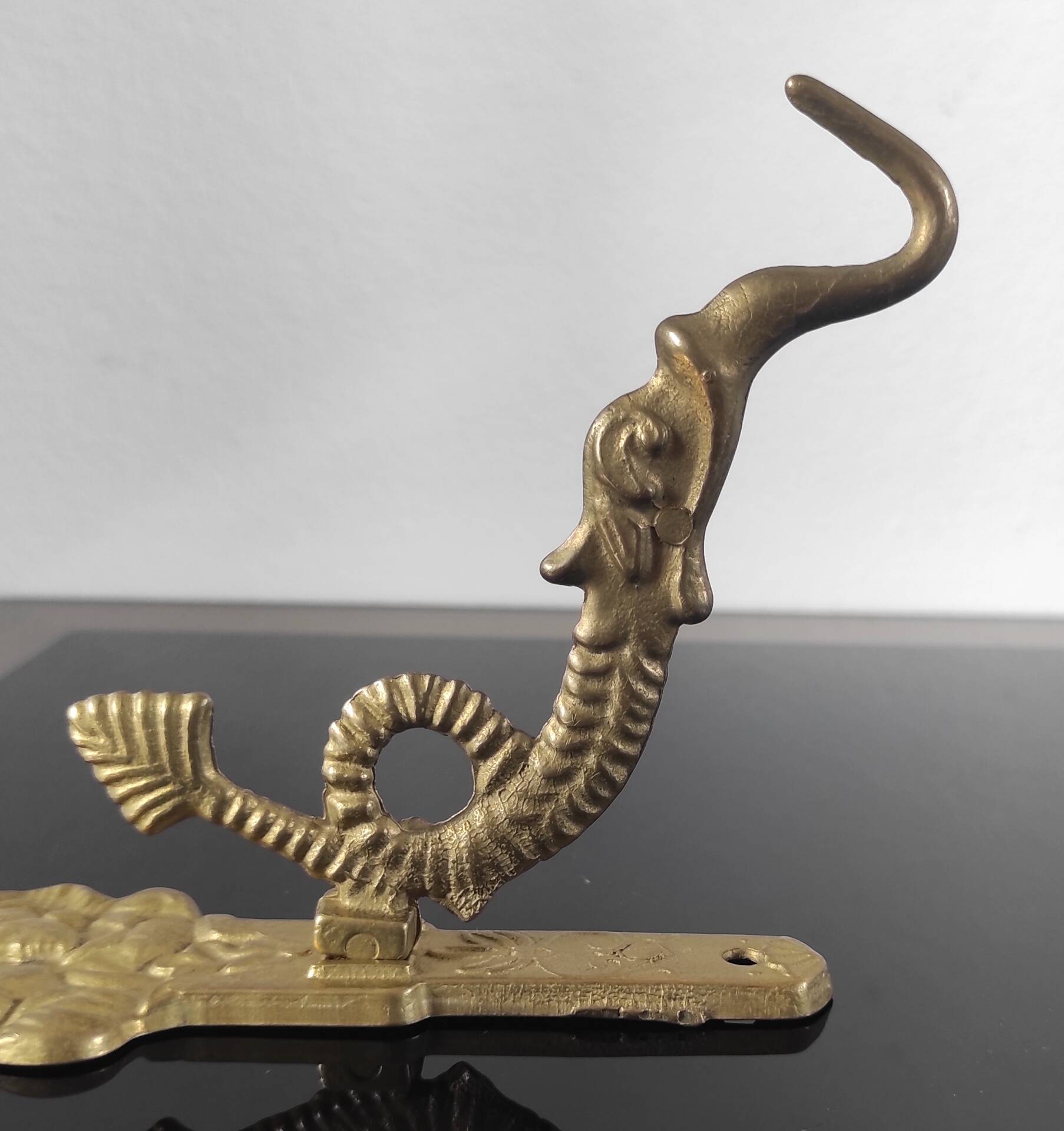 Vintage brass coat hook with marine creature motif and medallion.