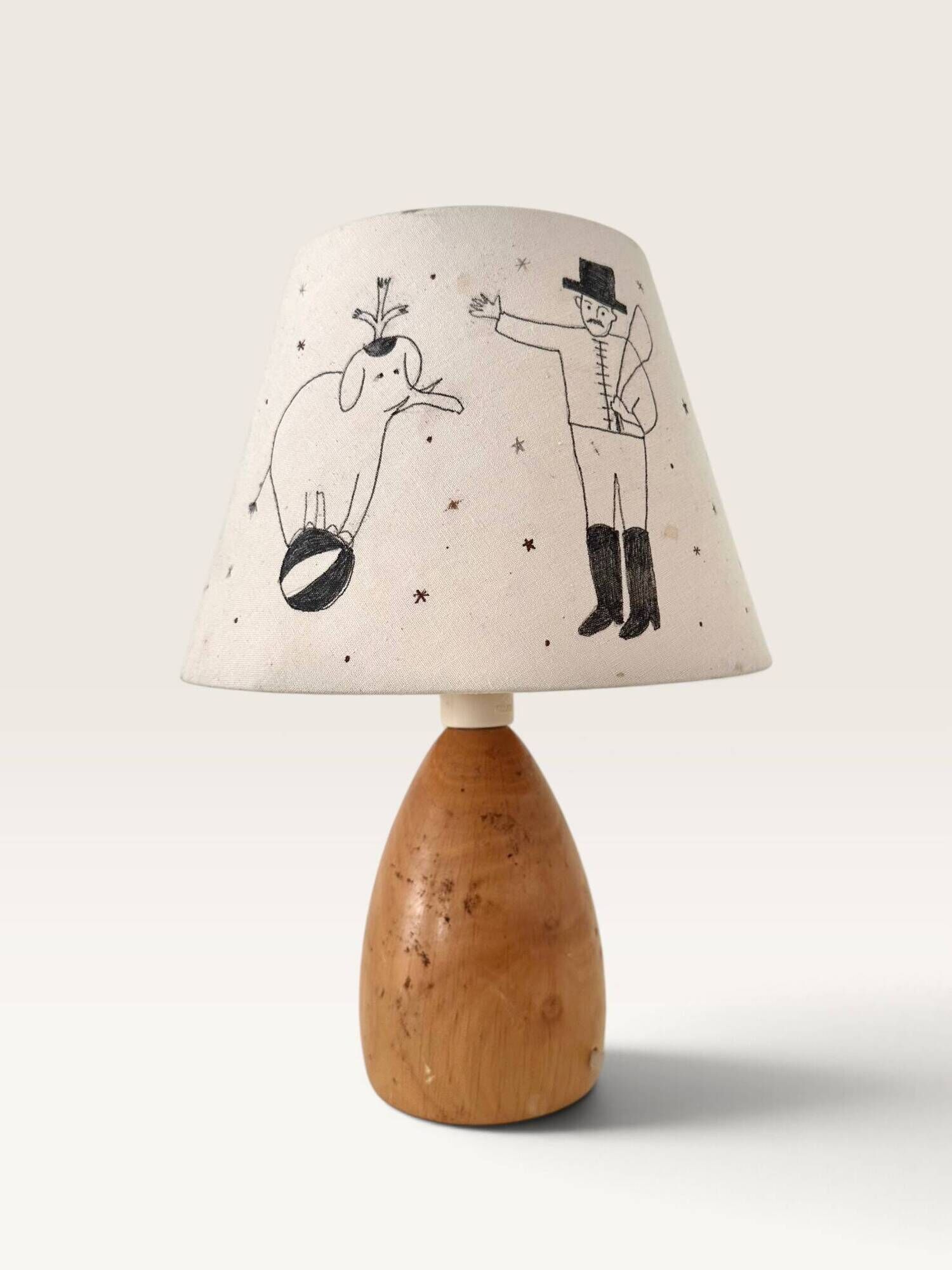 Wood-turned lamp with a hand-drawn lampshade, circus patterns.