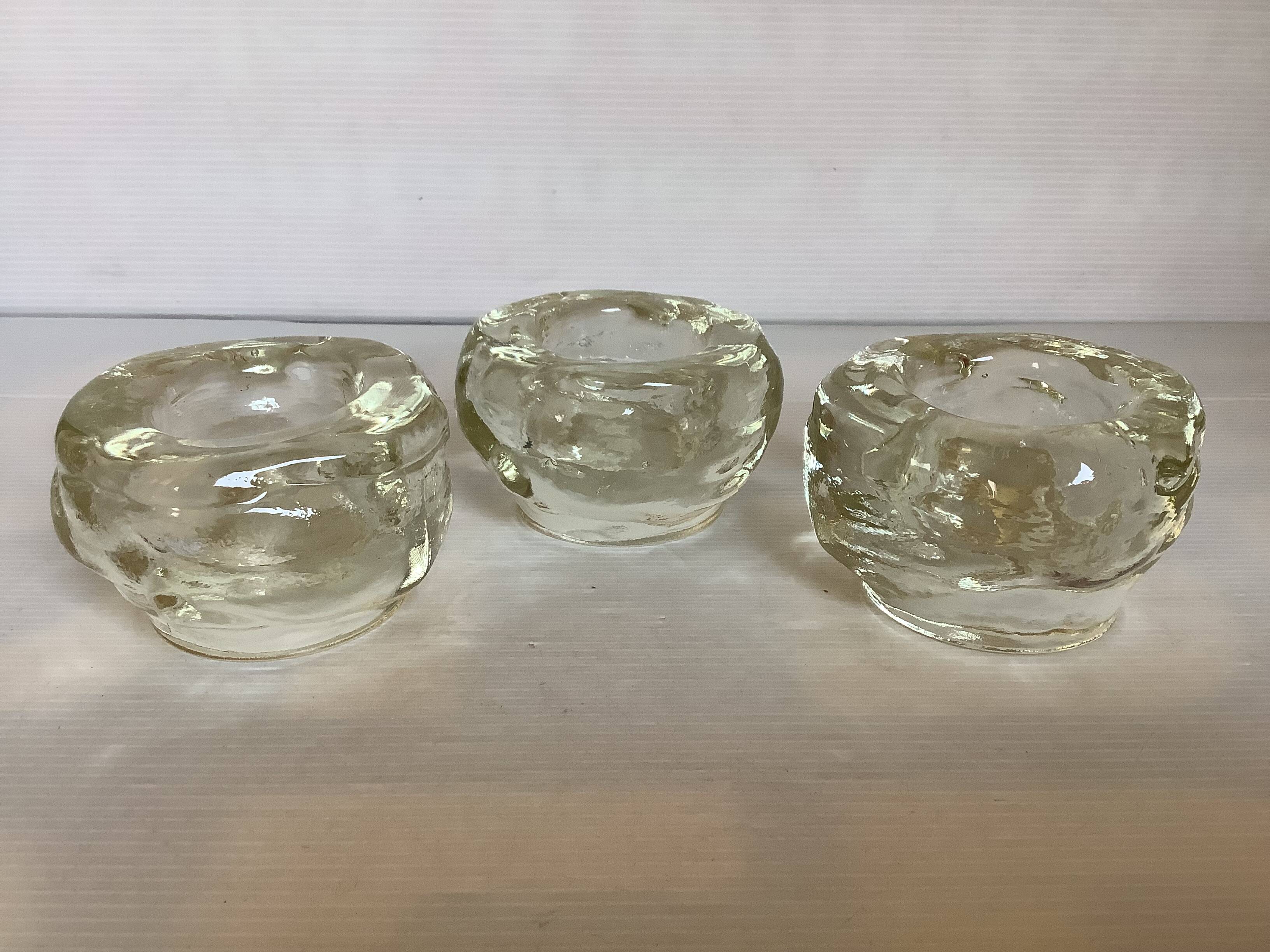 Set of three thick moulded glass candle holders.