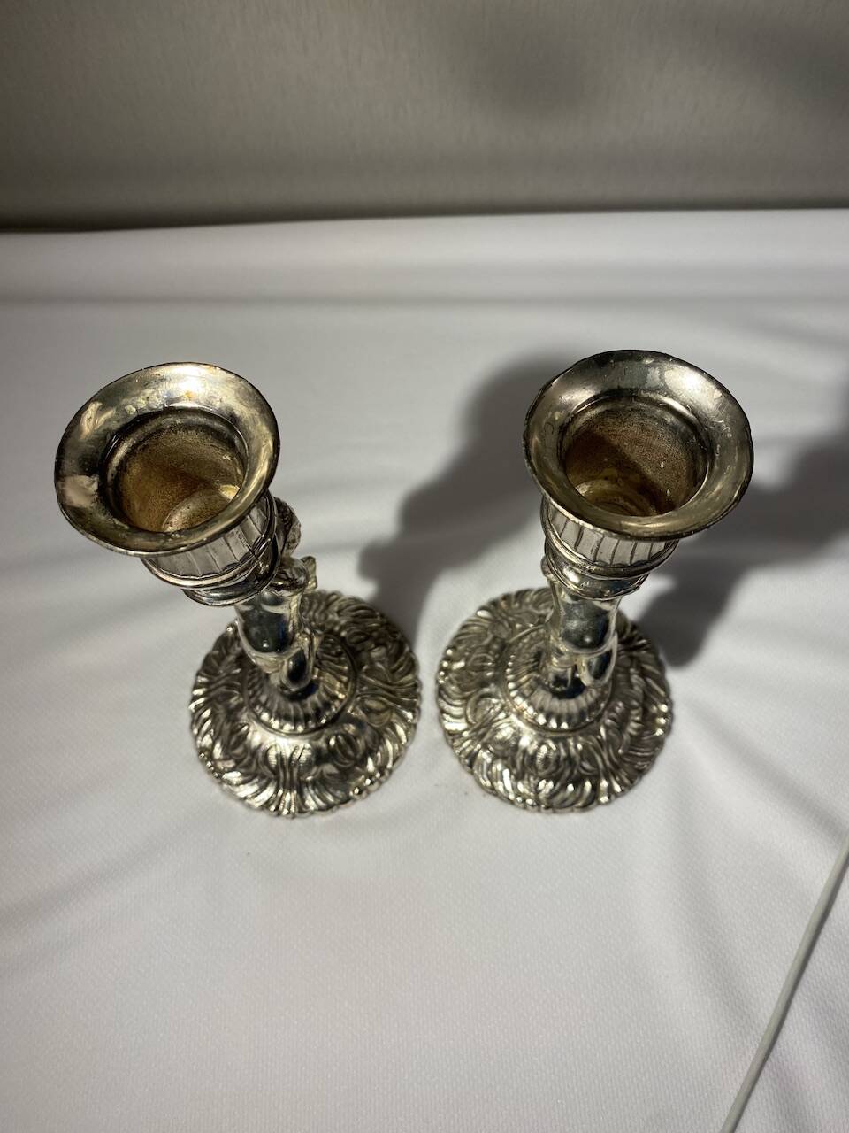 Two silver-plated metal candlesticks decorated with cherubs, 20th century