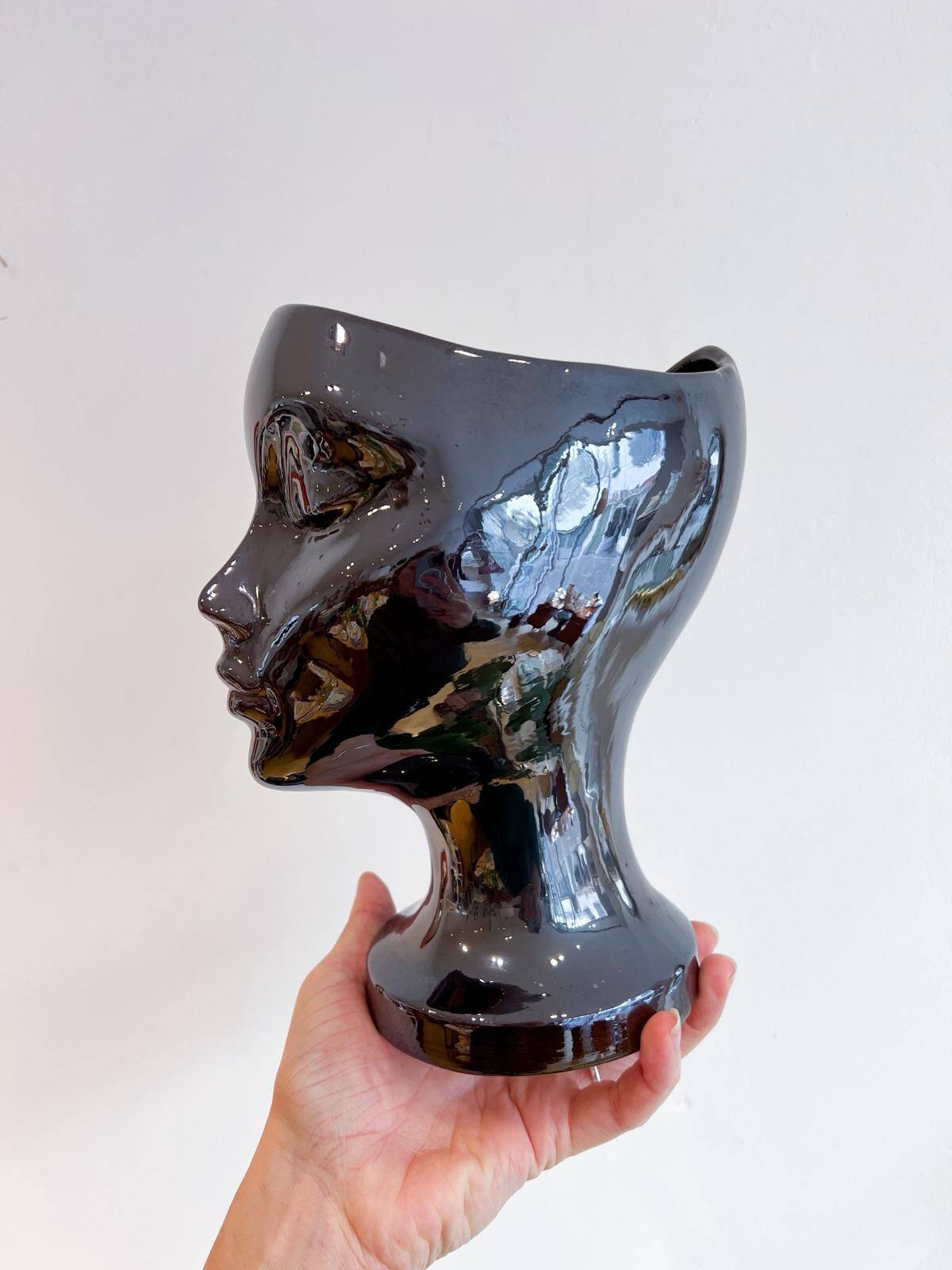 Black ceramic vase with a woman's face.