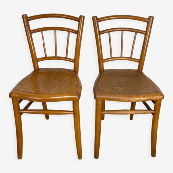 Pair of curved wood bistro chairs and studded and perforated seat