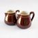 Duo of brown enamel pitchers