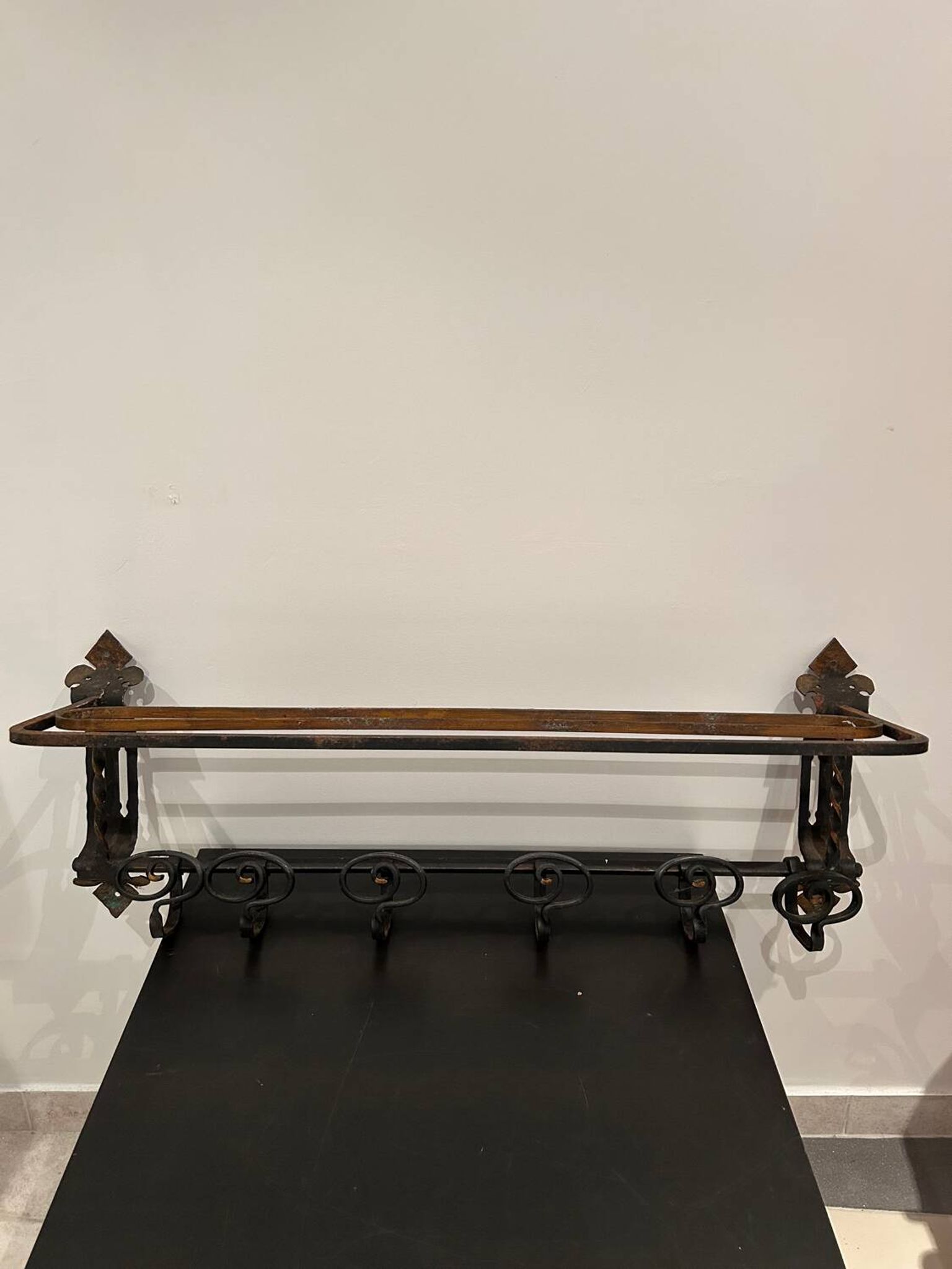 Large antique wall-mounted coat rack in wrought iron.