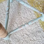 Antique tripod stool with blue striped seat.