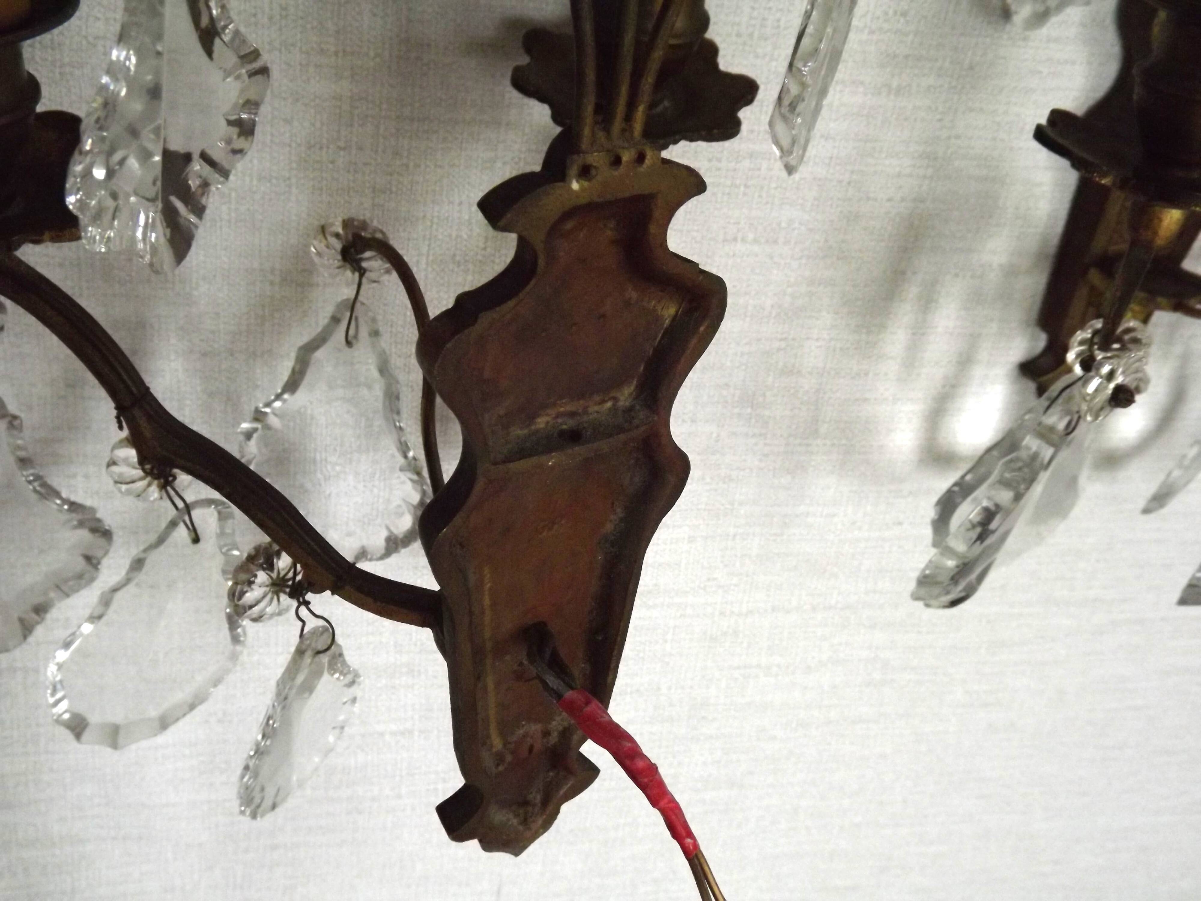 Pair of French antique brass double wall lights with assorted crystals.