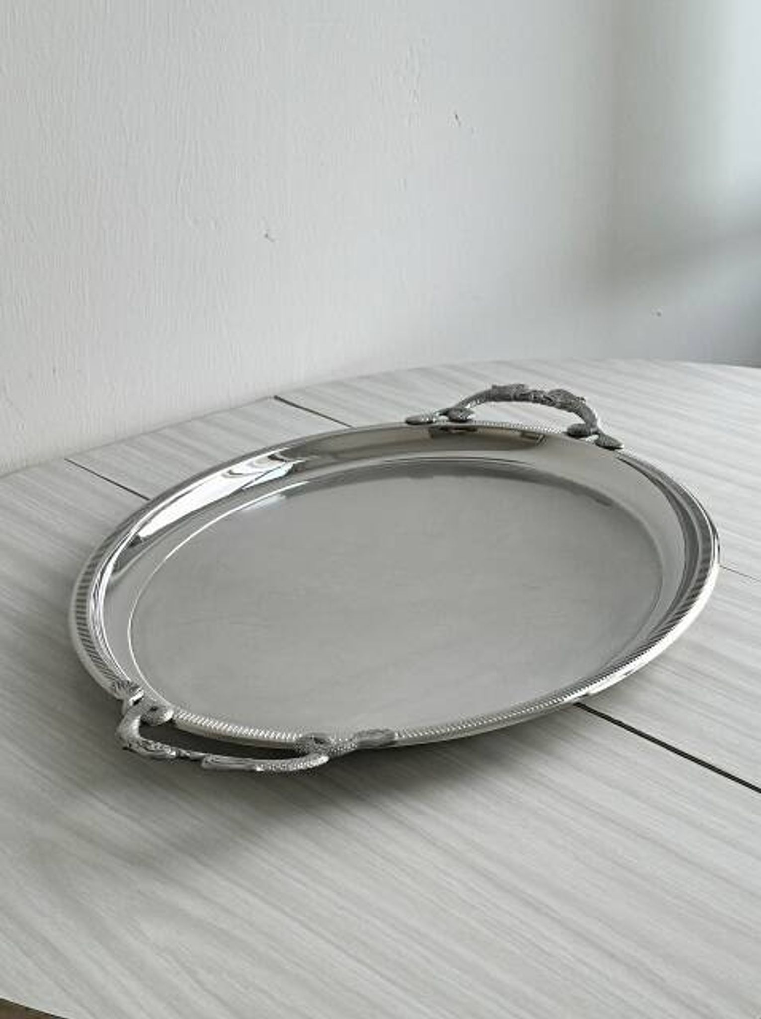 Large stainless steel serving platter with fish-shaped handles.
