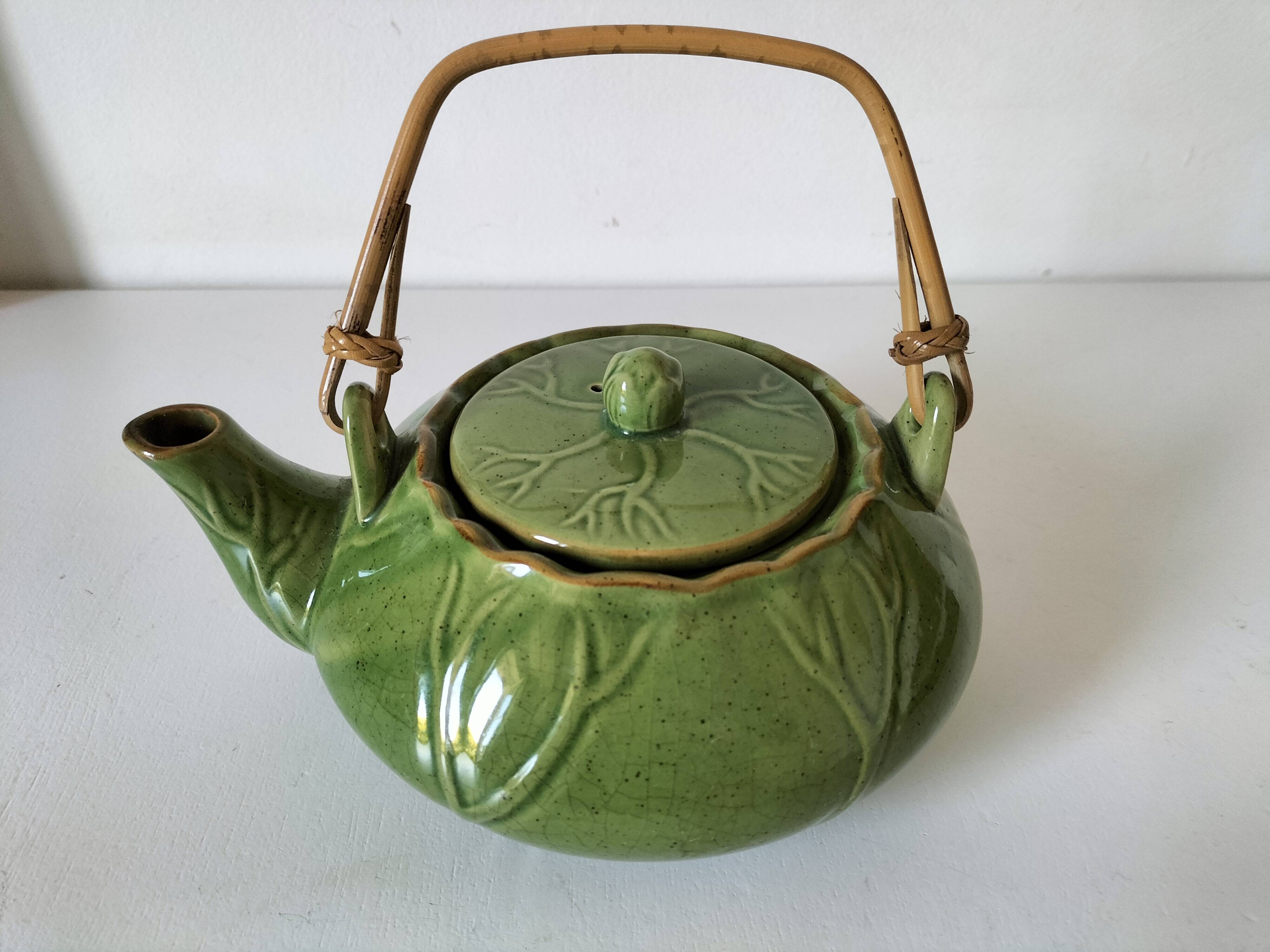 Vintage green teapot with lotus decoration and bamboo handle.