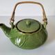 Vintage green teapot with lotus decoration and bamboo handle.
