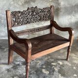 Small antique Indonesian bench in carved teak with plant and floral motifs.