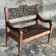 Small antique Indonesian bench in carved teak with plant and floral motifs.