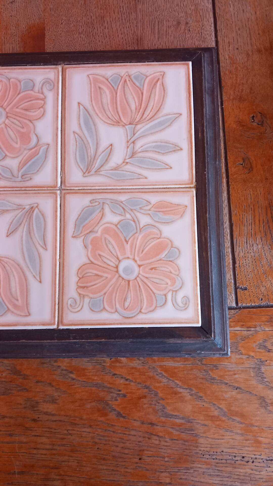 Ceramic tile trivet with floral patterns in pastel tones.