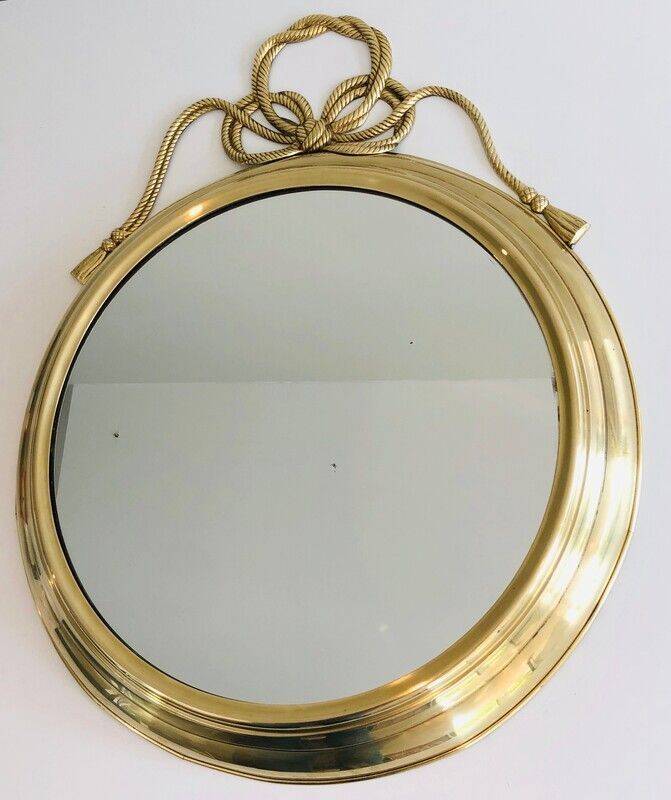 Large decorative oval mirror in brass adorned with a significant twisted bow.