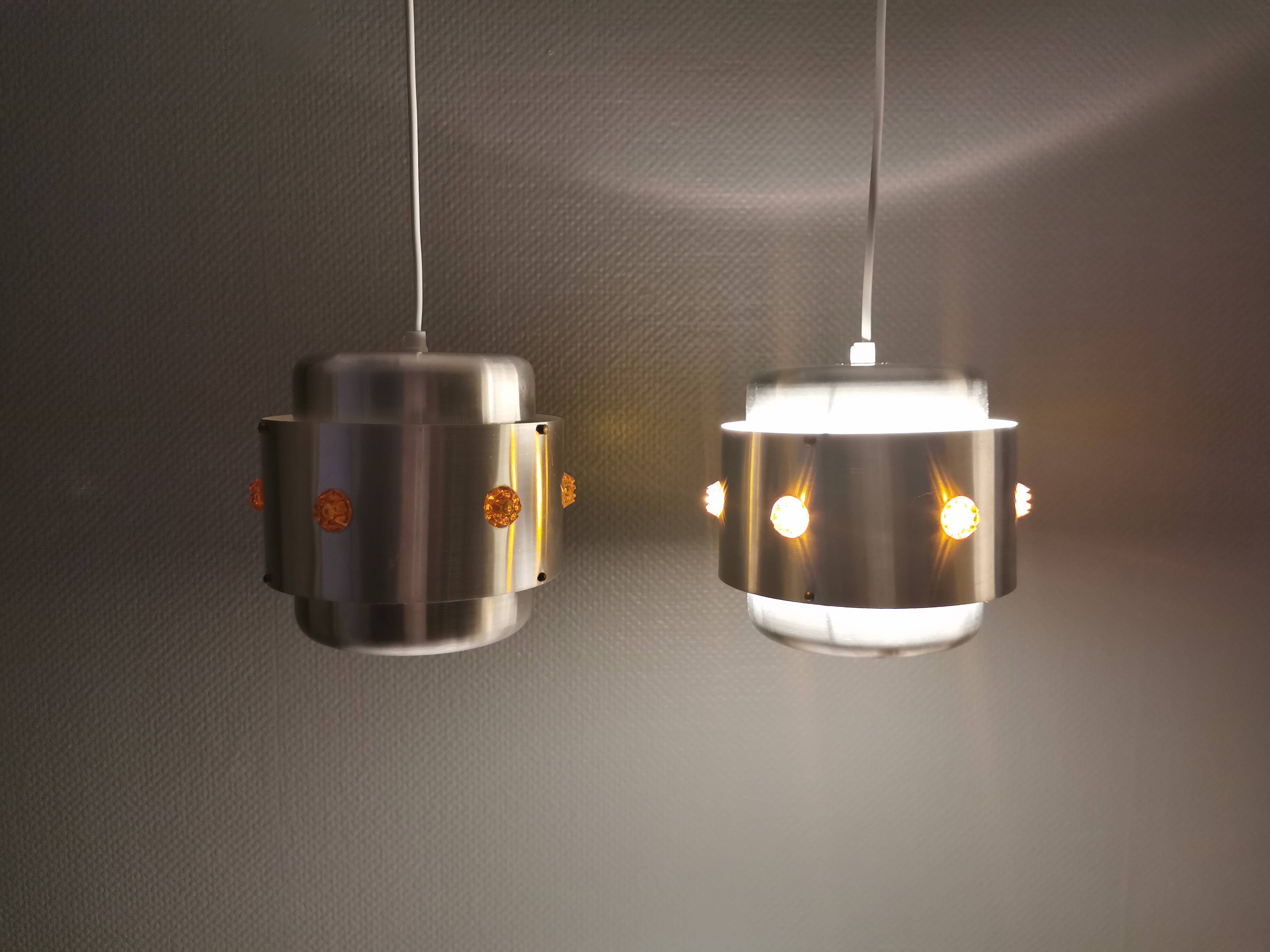 Two Space-Age hanging lamps, in silver-coloured aluminium with orange prisms.