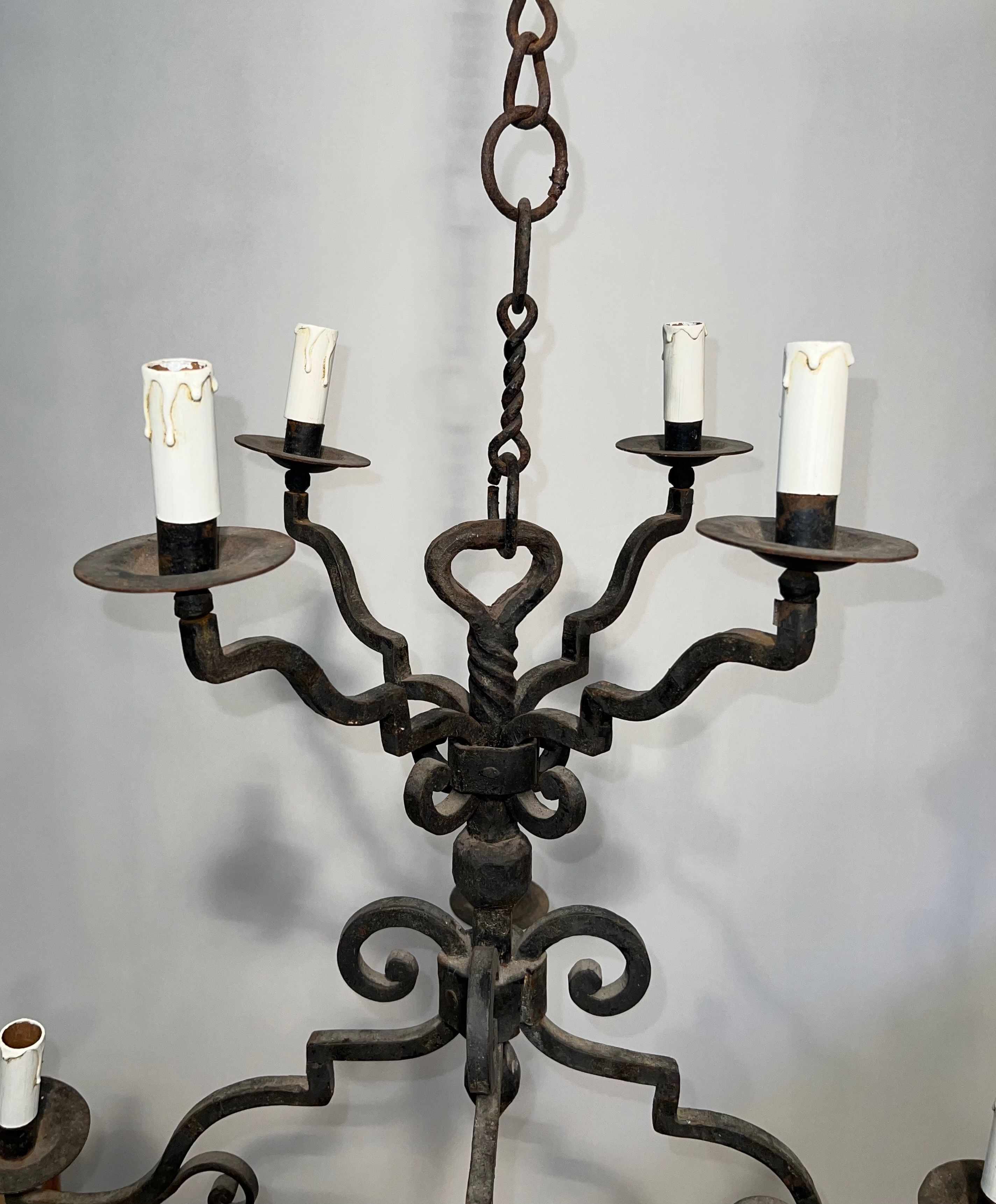 Two-tiered wrought iron chandelier with eight light arms in Gothic style.