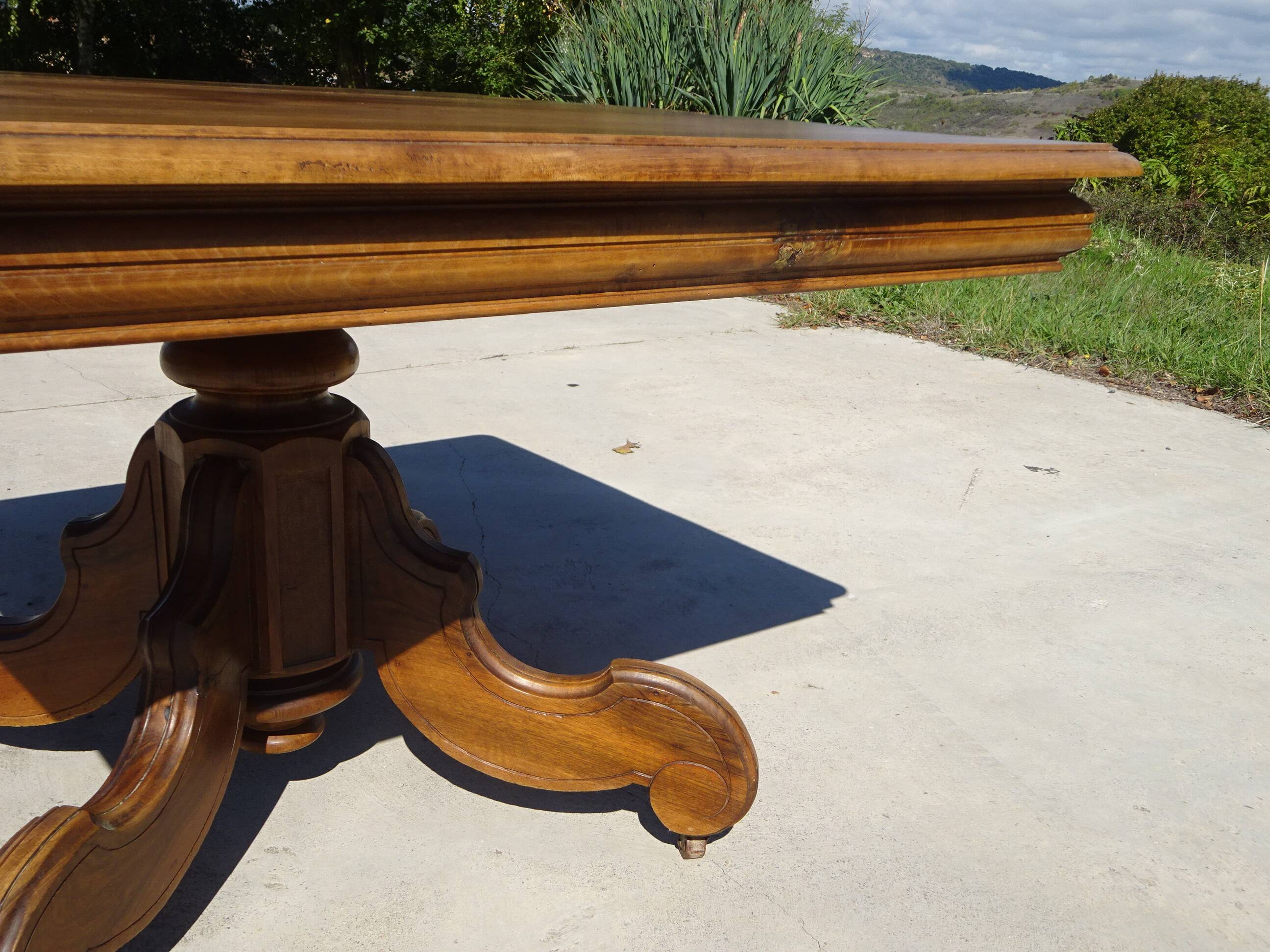 Old walnut table with a central leg.
