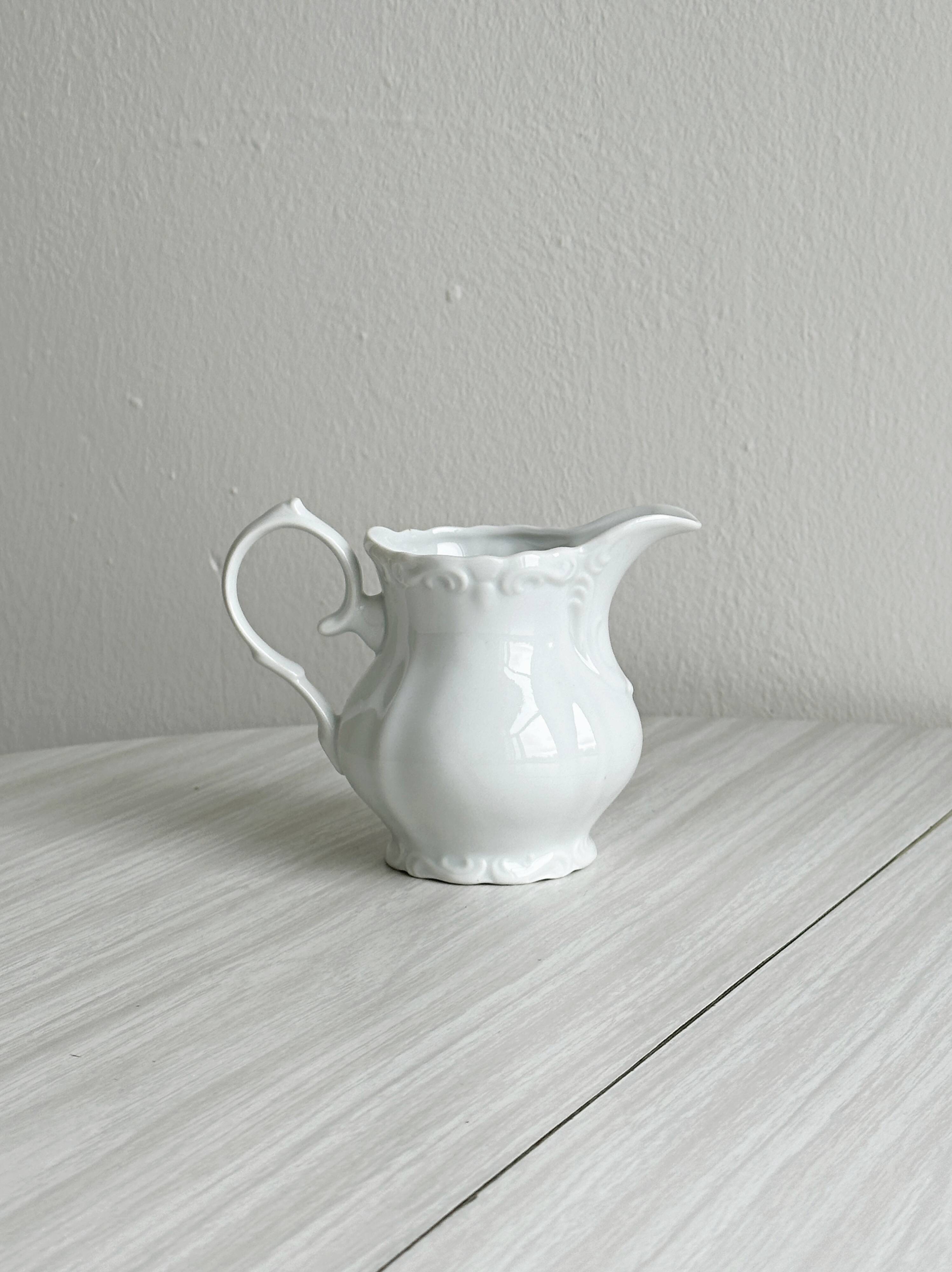Old white porcelain milk jug, cream jug with relief.