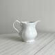 Old white porcelain milk jug, cream jug with relief.