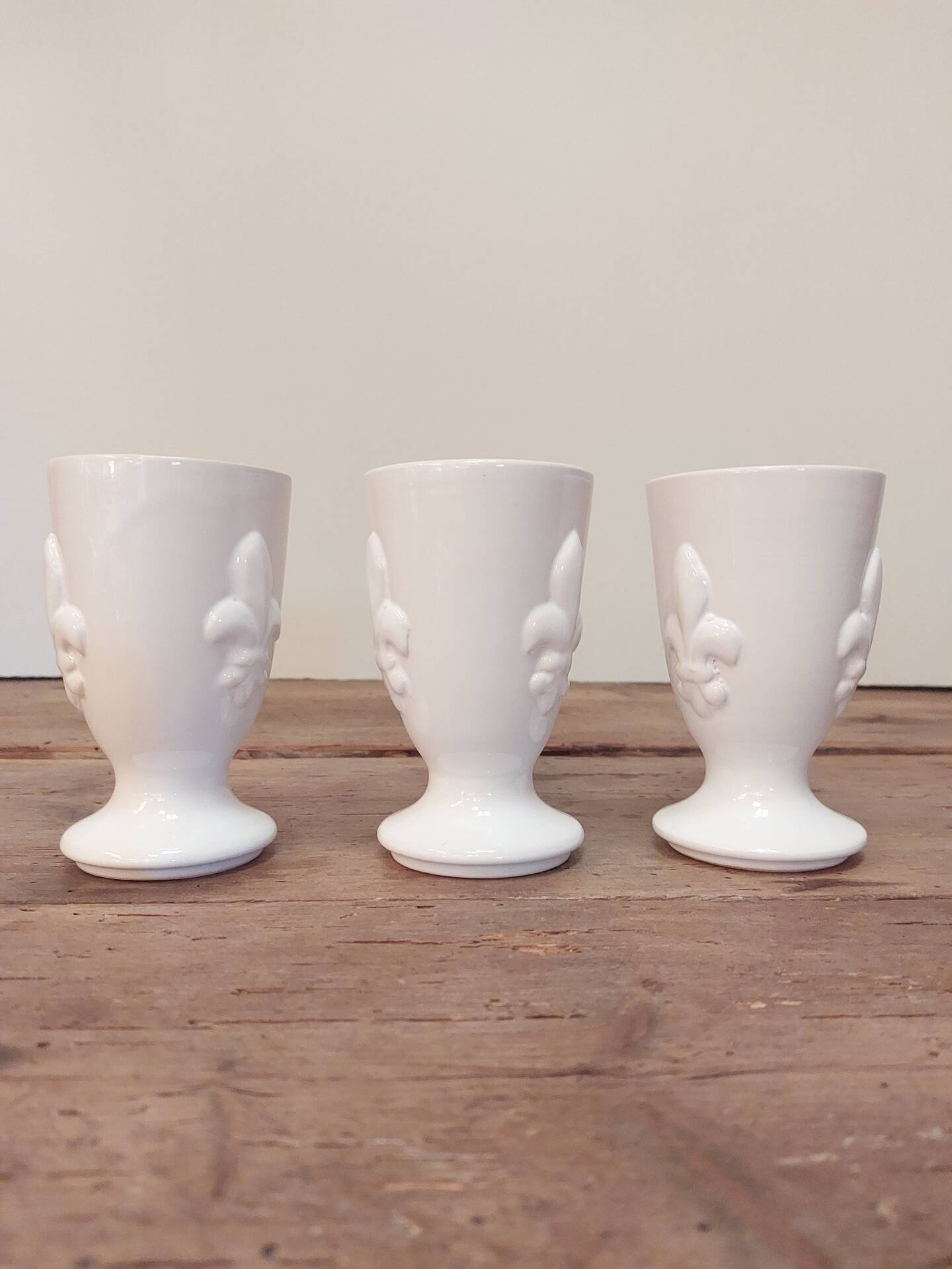 Three antique cups decorated with fleur-de-lis.