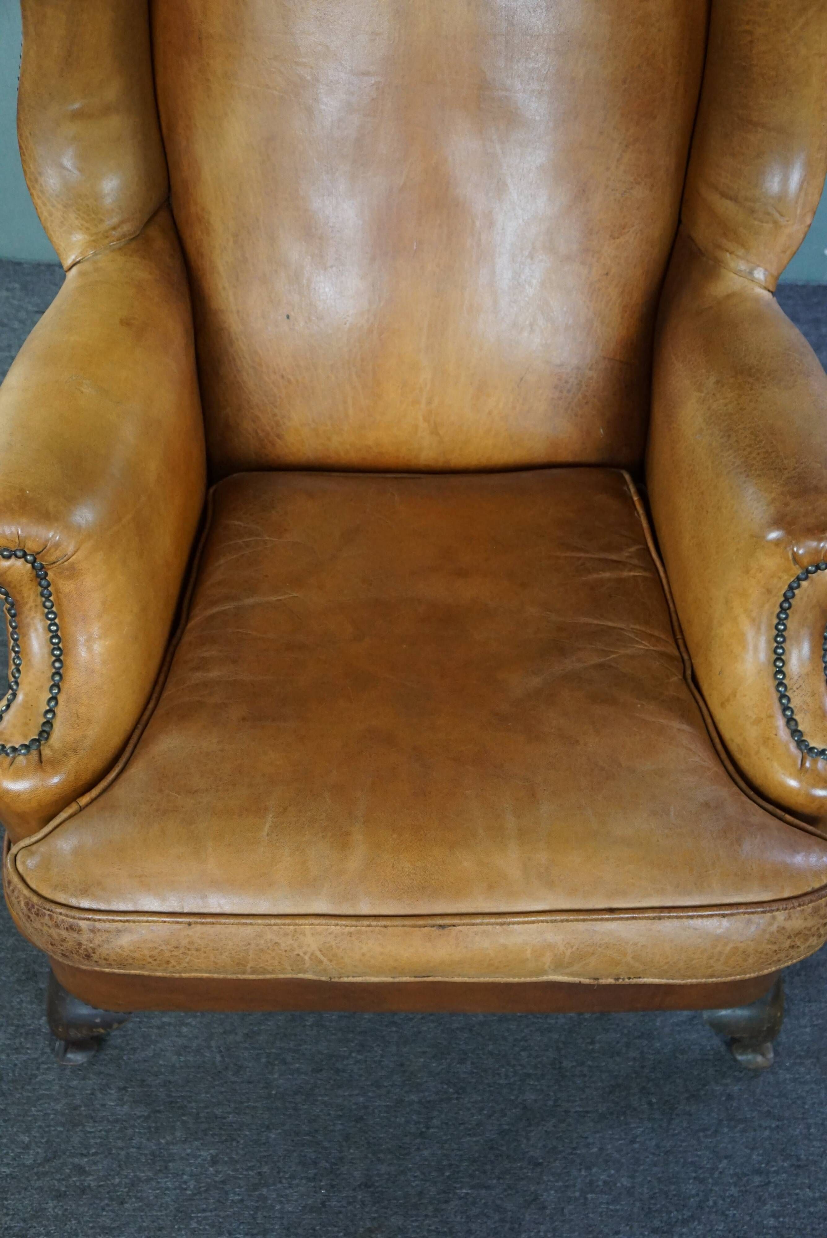 Old wingback armchair made of sheep leather in a correct condition