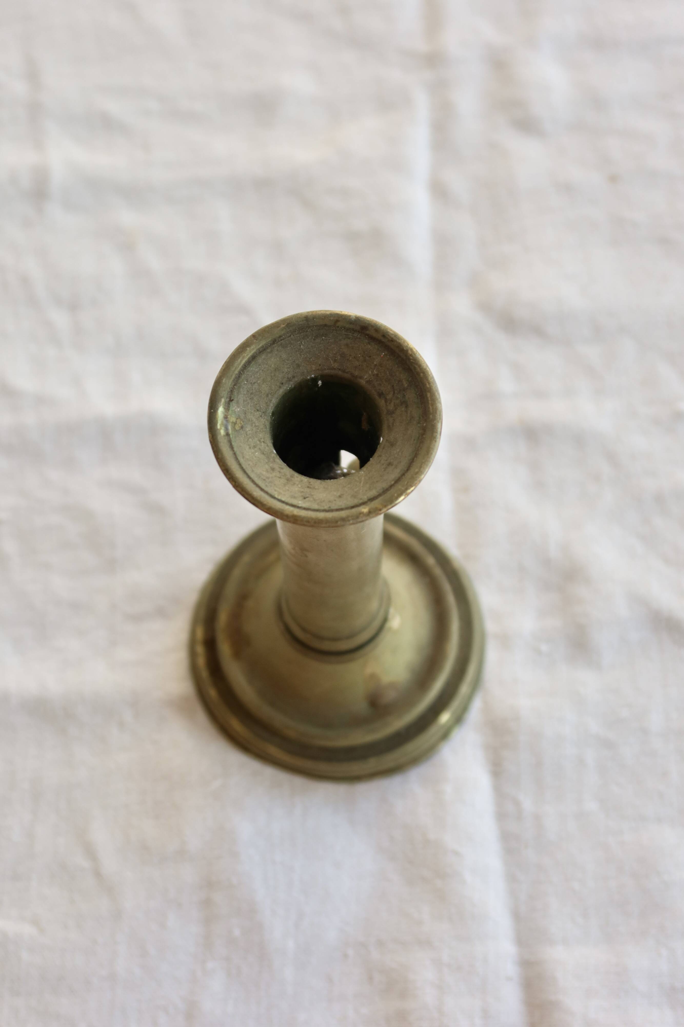 Antique brass candlestick with a push button.