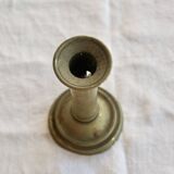 Antique brass candlestick with a push button.