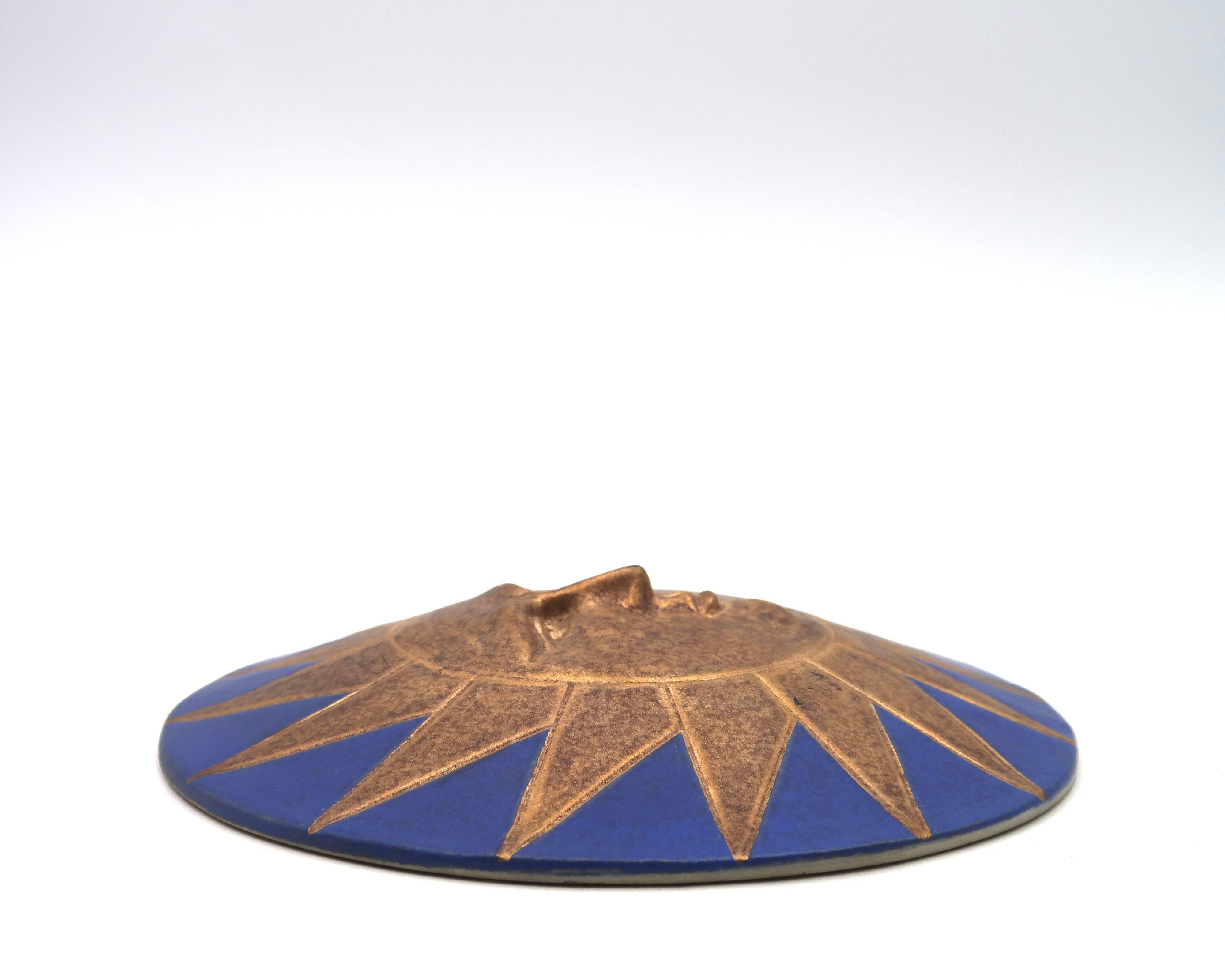 Relief mural signed in ceramic, sun with blue and gold face, 1990s.