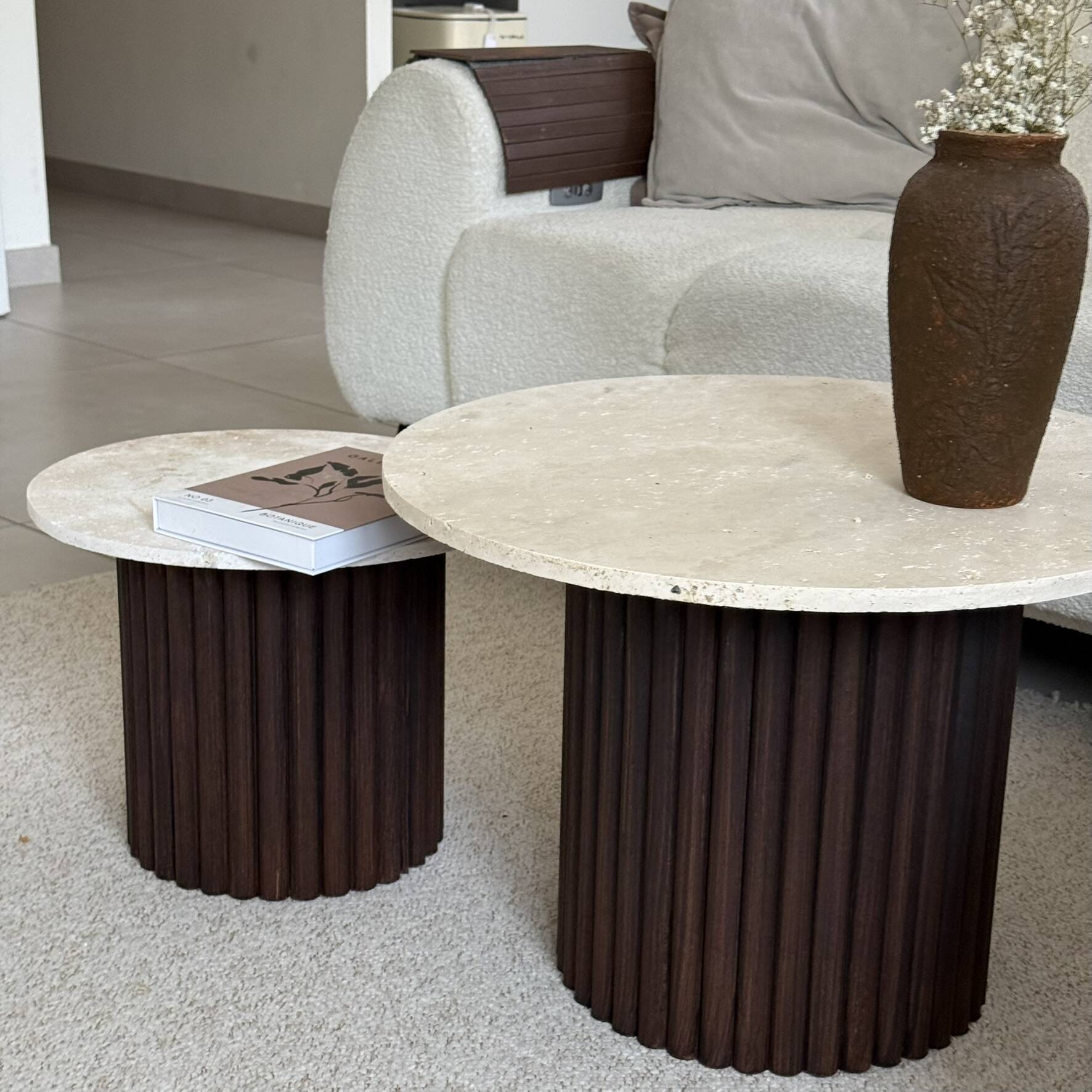 Round nesting coffee table in travertine and dark fluted wood.