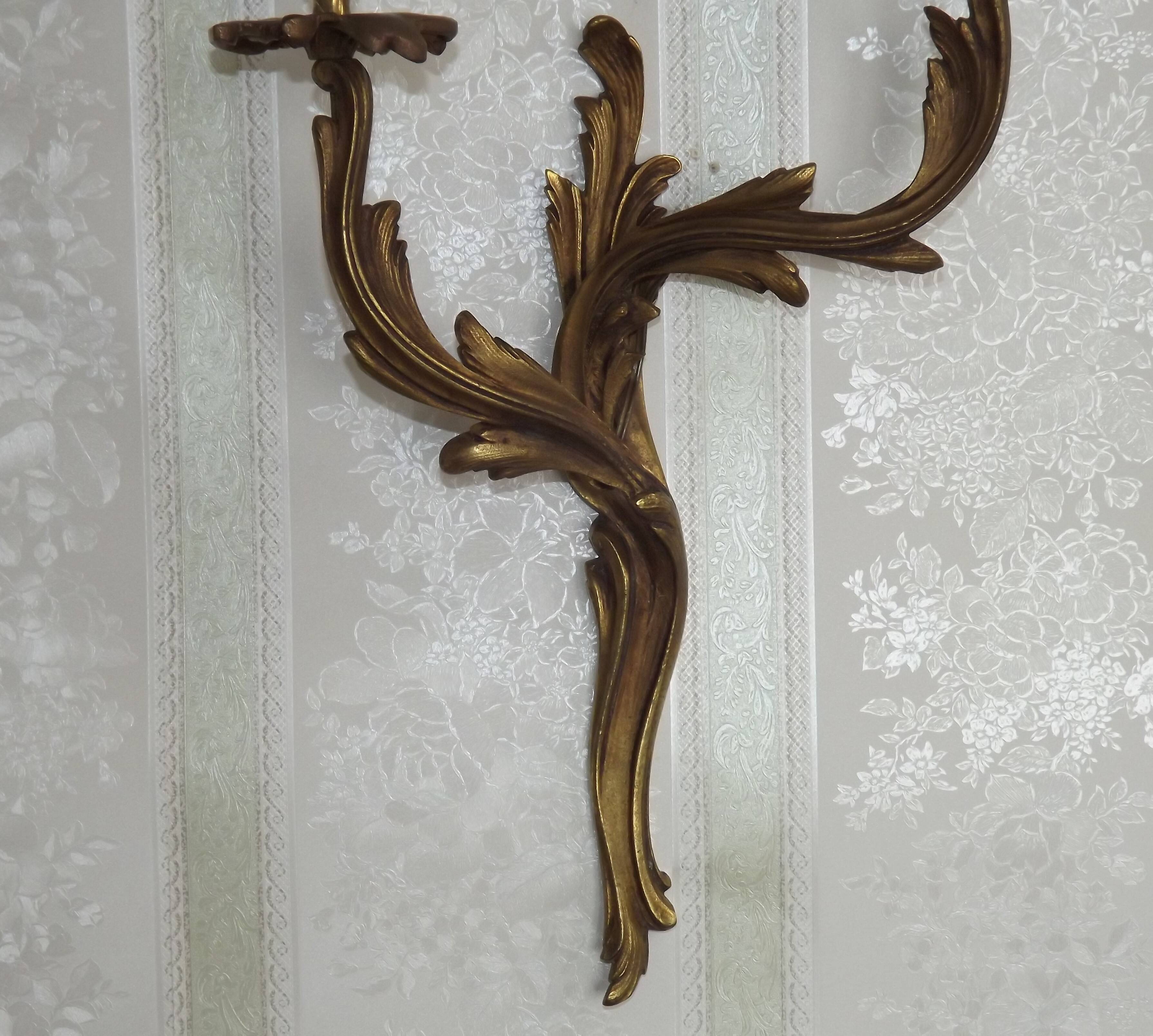 Apply two bronze wall lights decorated with acanthus leaves.