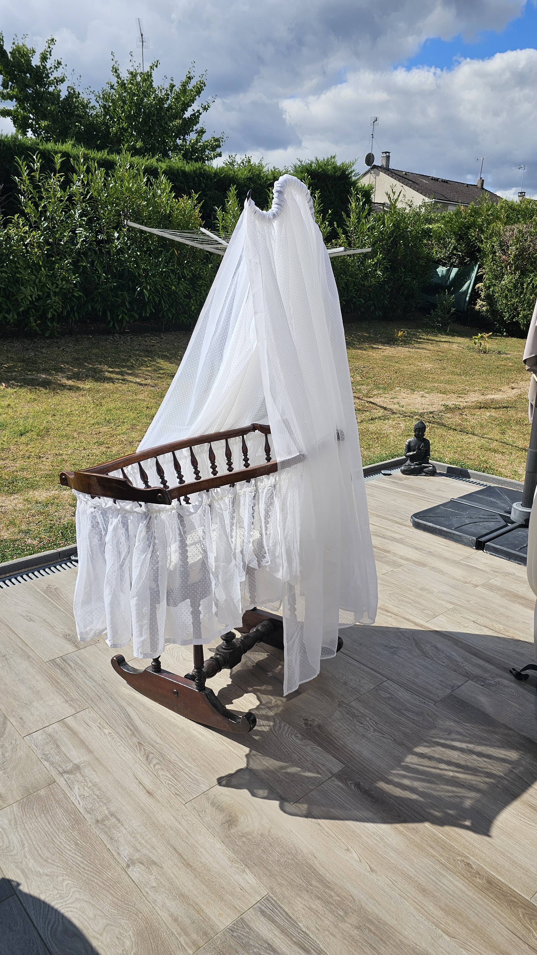 Old wooden rocking chair with turned legs and plumetis fabric.