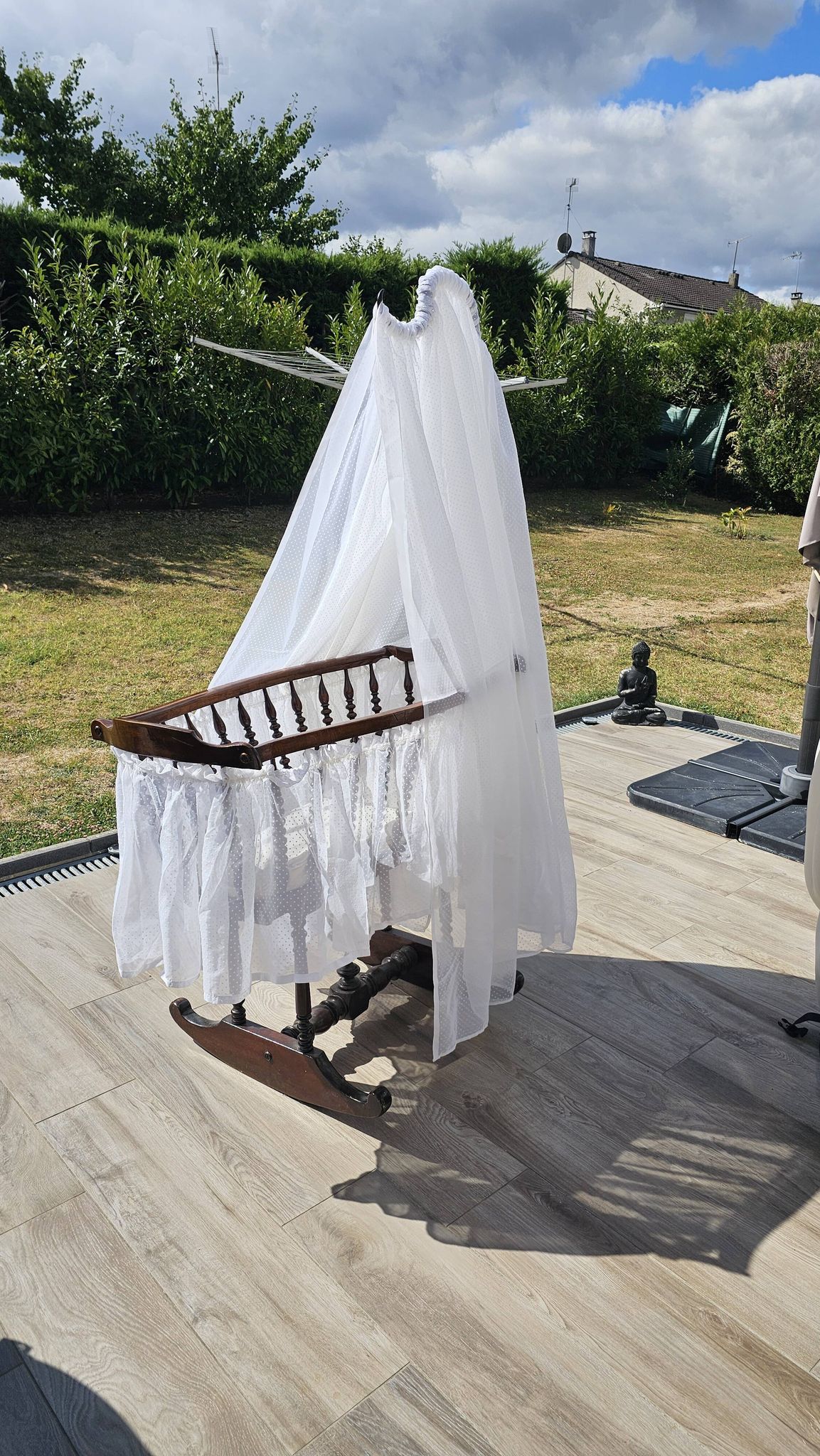 Old wooden rocking chair with turned legs and plumetis fabric.
