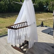 Old wooden rocking chair with turned legs and plumetis fabric.