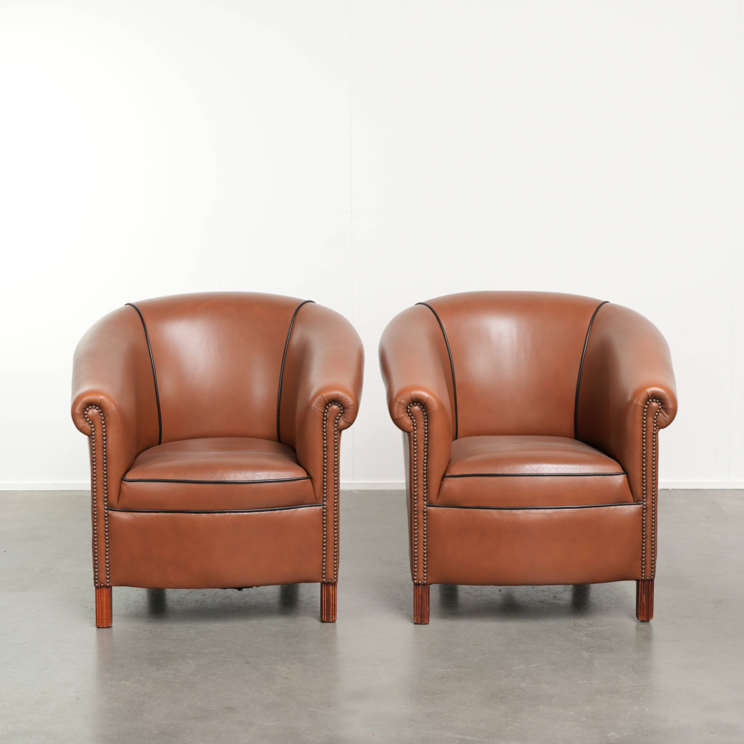 Ensemble de 2 fauteuils club en cuir de vache en bon état dans le style anglais.