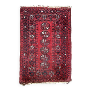 Bukhara Oriental carpet in wool with geometric patterns on a red background,