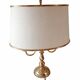 Empire style brass bouillotte lamp with an ivory oval shade.