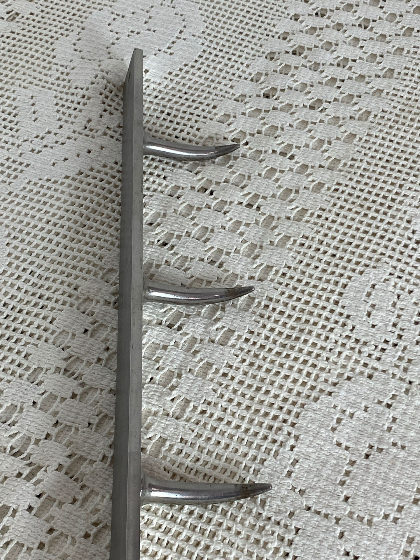 Stainless steel butcher's hook, known as a "wolf tooth bar."
