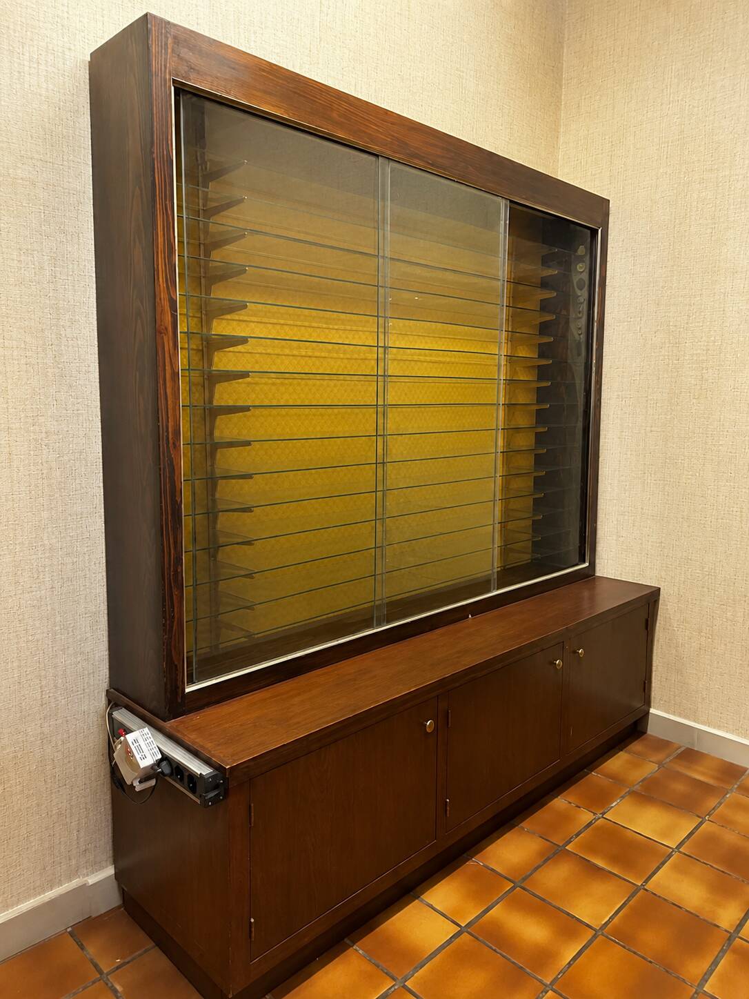 Vintage wooden and glass display cabinet, 15 shelves, gold background.