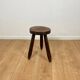 Small brutalist tripod stool in solid wood.