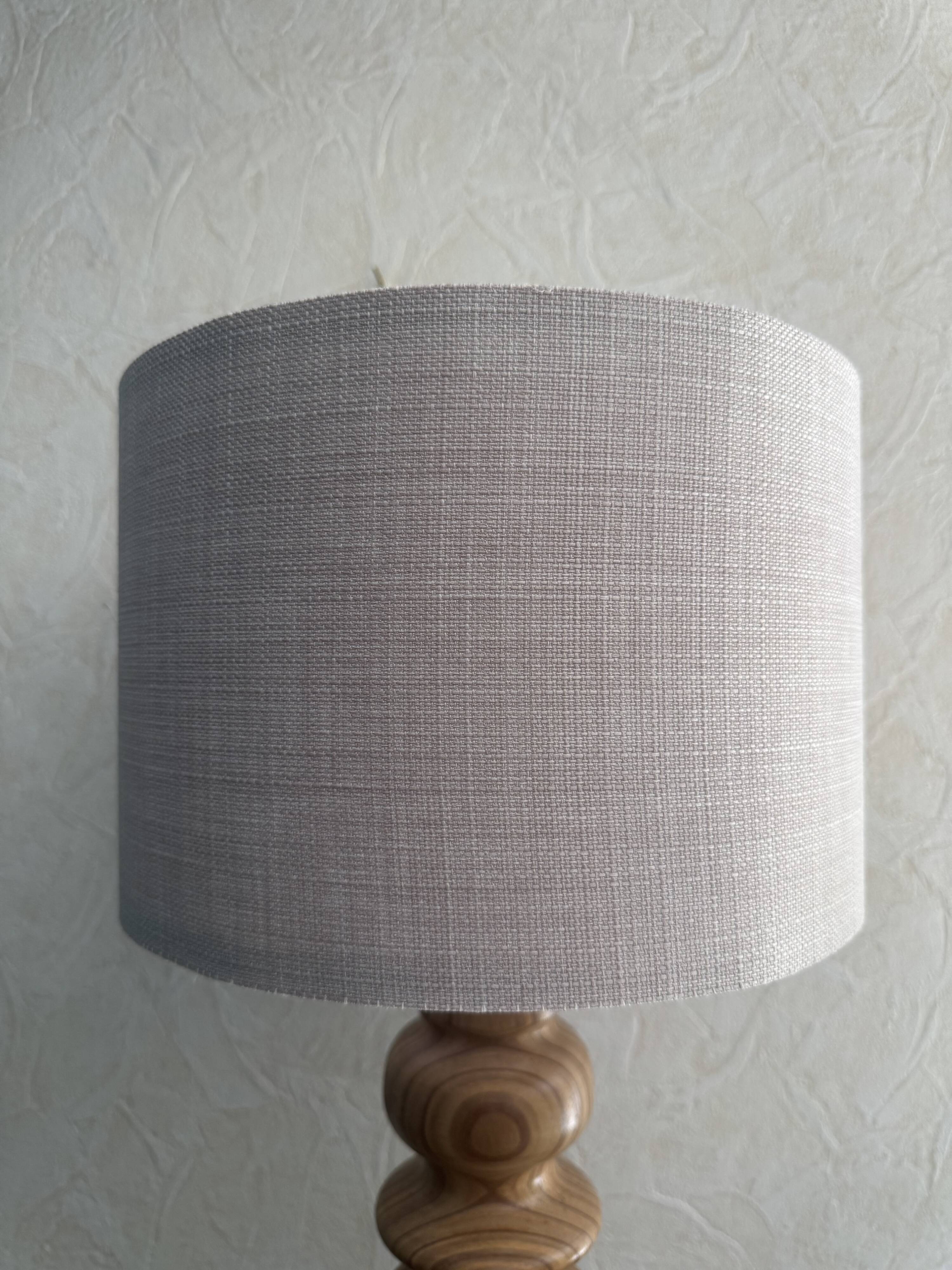 Wooden turned totem lamp with a linen shade in a vintage Scandinavian style.